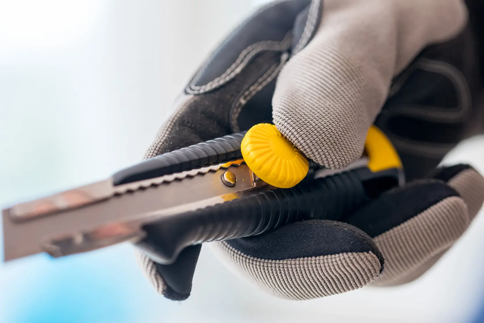 STANLEY 0-10-418 utility knife with yellow dial, held in gloved hand, close-up photography.