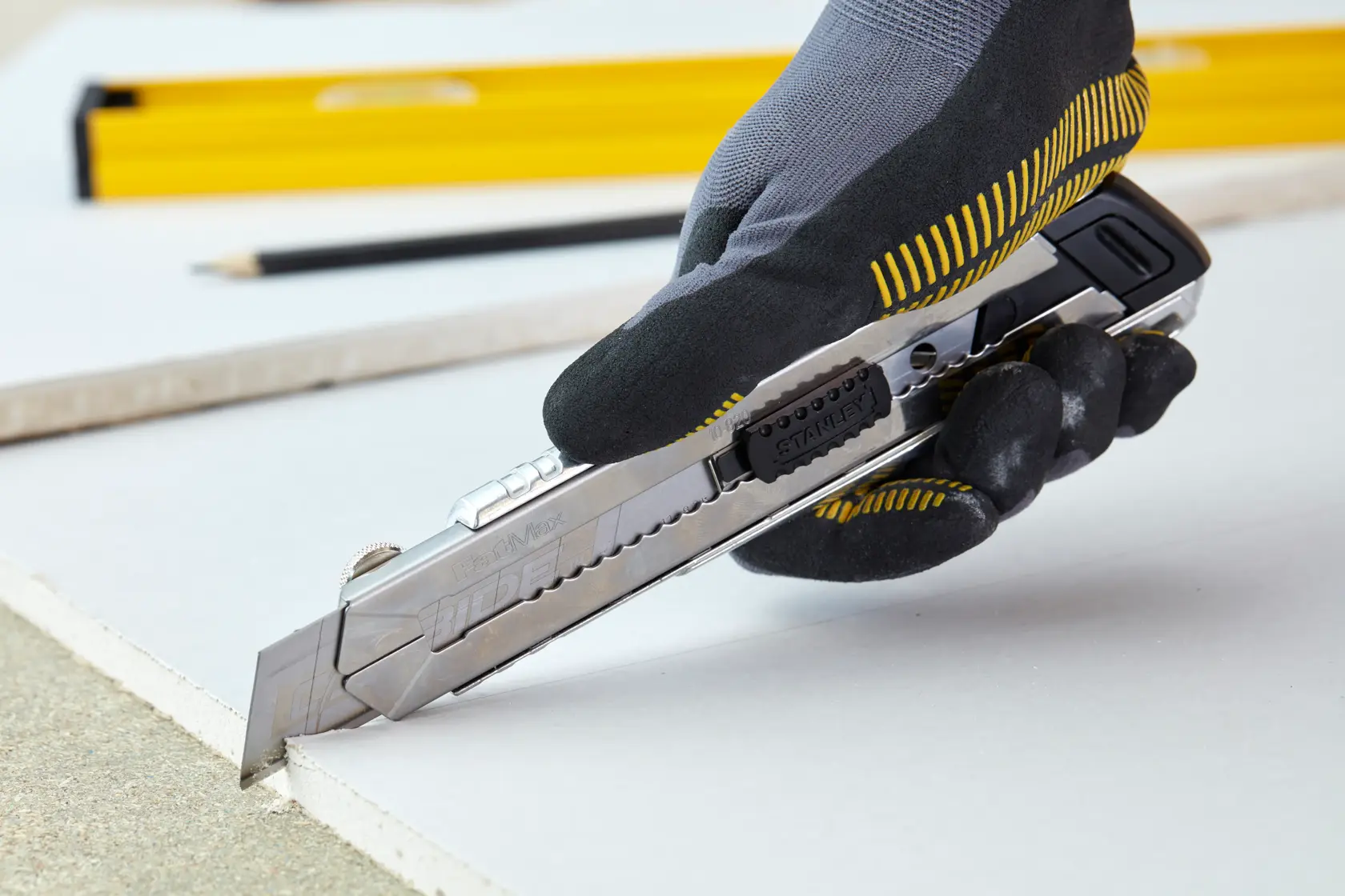 STANLEY 0-10-820 utility knife cutting drywall held by gloved hand, side angle photography.