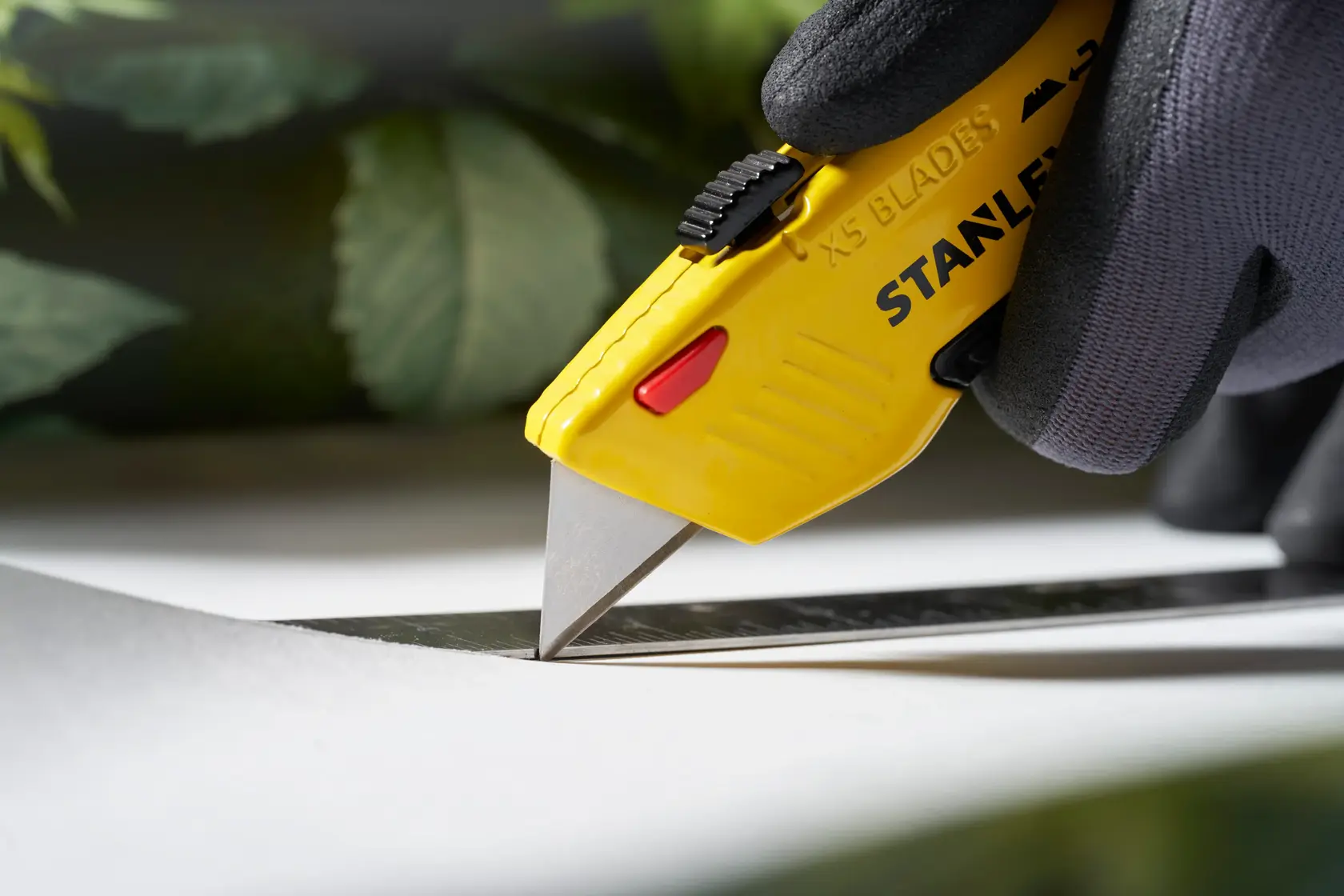 Stanley 0-11-921 Cutter-Messer Fotografie mit gelbem Griff schneidet entlang eines Metalllineals.