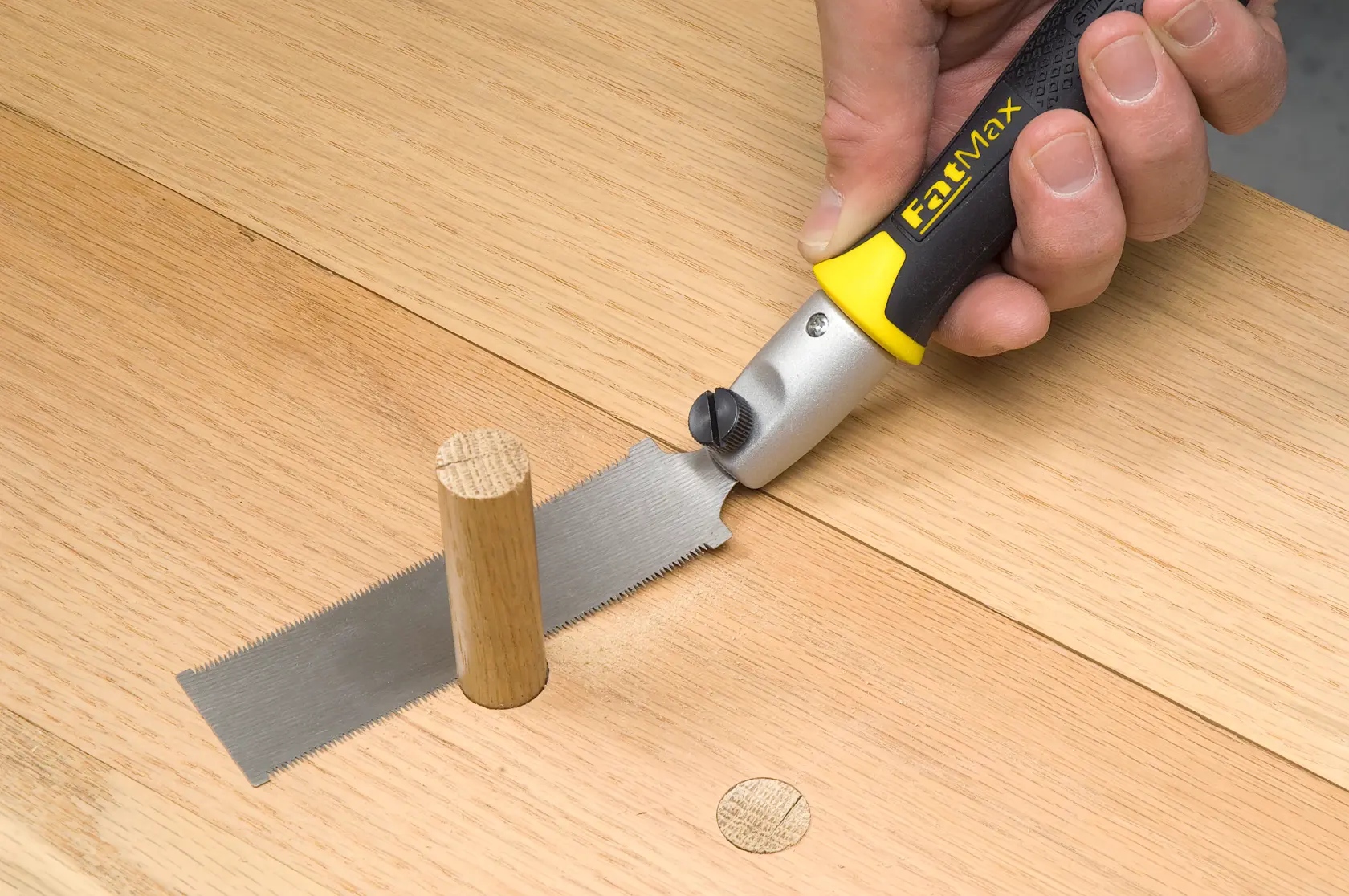 STANLEY 0-20-331 flush cut saw with black and yellow handle cutting wood dowel, close-up photo.