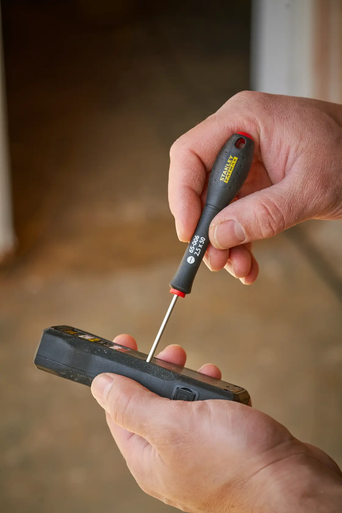 Photography of STANLEY 0-65-006 precision screwdriver held in hand, used on an electronic device.