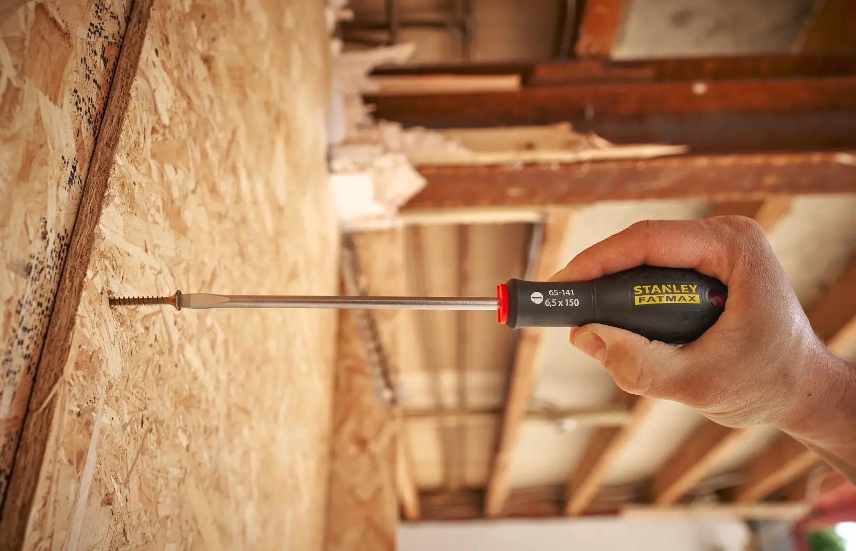 Photo of STANLEY 0-65-141 screwdriver being used to drive a screw into plywood, close-up on handle and tool.