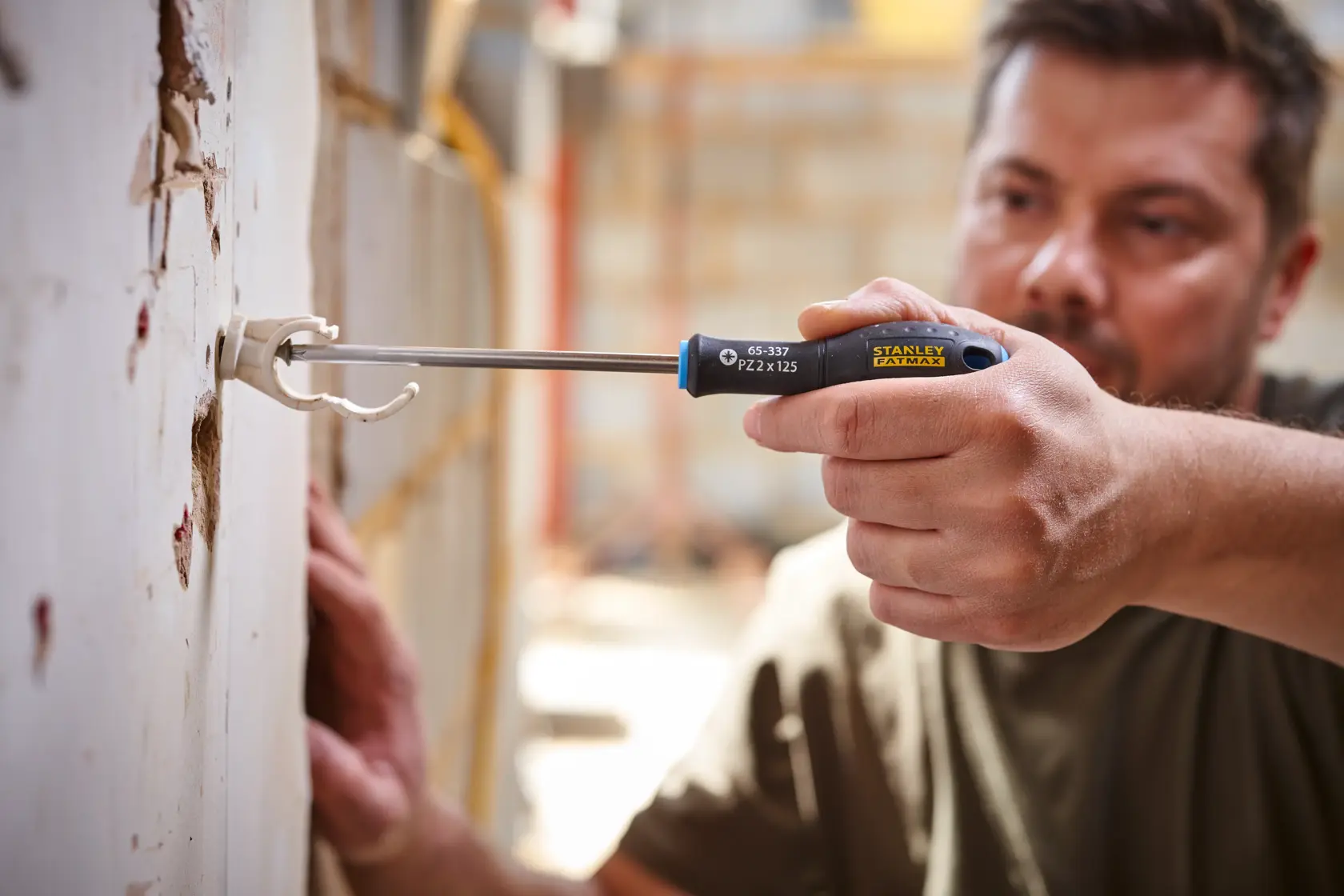 Photo of STANLEY 0-65-337 screwdriver used to install fixture in drywall, close-up view.