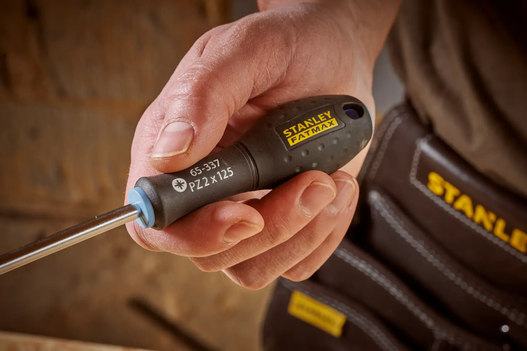 Photo of STANLEY 0-65-337 screwdriver with black handle and yellow logo, held in hand, close-up view.