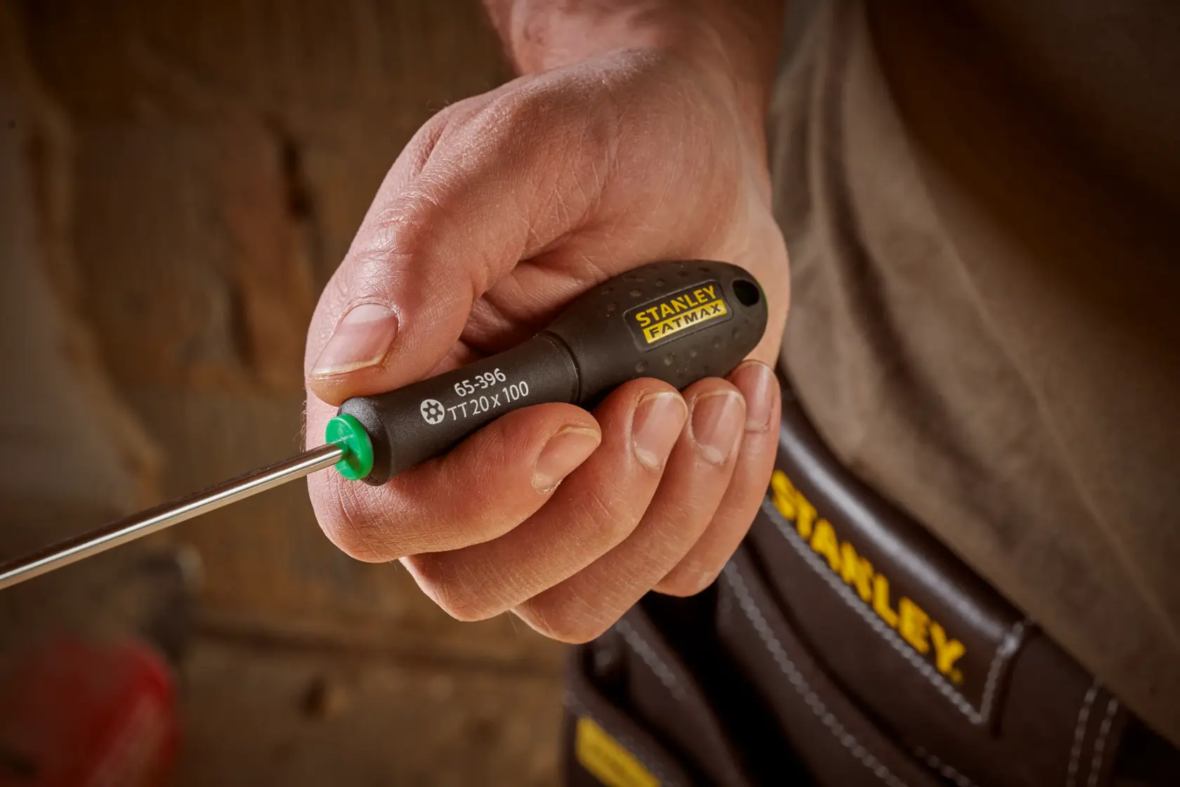 Photo of STANLEY 0-65-396 screwdriver with black and yellow handle held in hand, tool pouch in background.