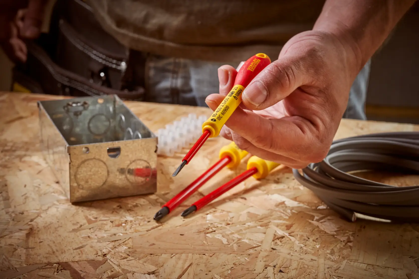 STANLEY 0-65-410 insulated screwdriver set with red and yellow handles on a workbench with electrical materials.
