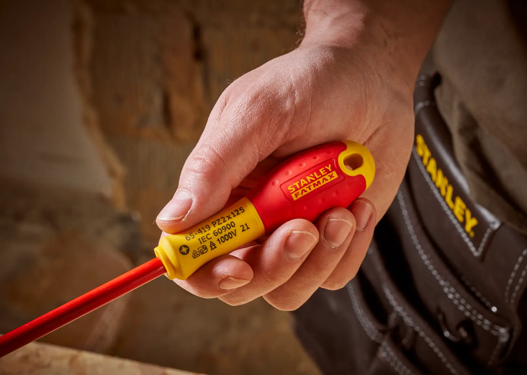 STANLEY 0-65-419 insulated screwdriver with red and yellow handle held in hand, close-up view.