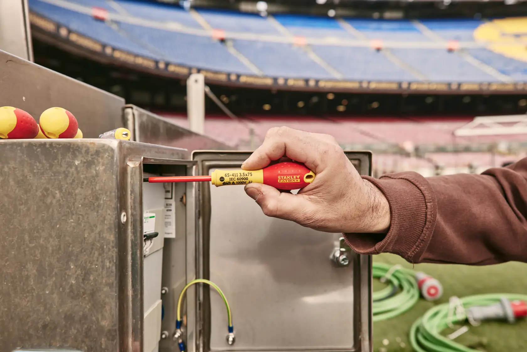 STANLEY 0-65-443 insulated screwdriver used at electrical box outdoors, red and yellow handle visible.