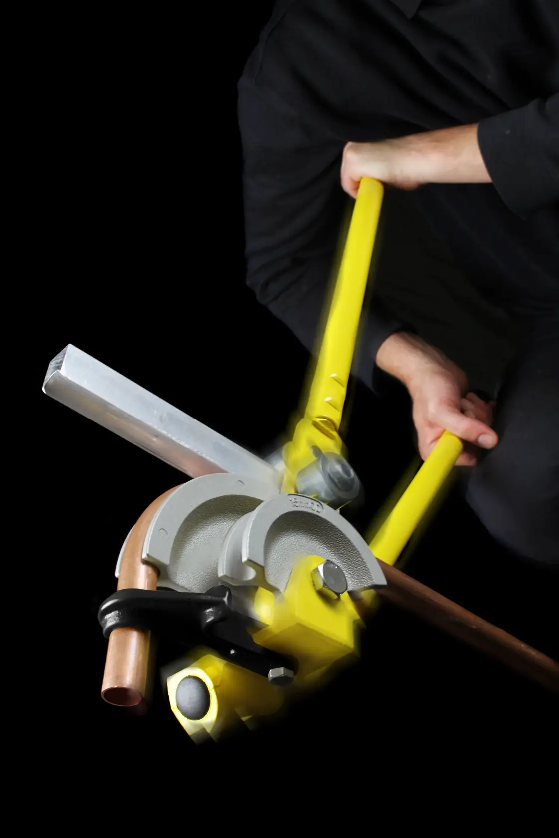 STANLEY 0-70-452 pipe bender with yellow handles shown bending a copper pipe, photographed with user action.