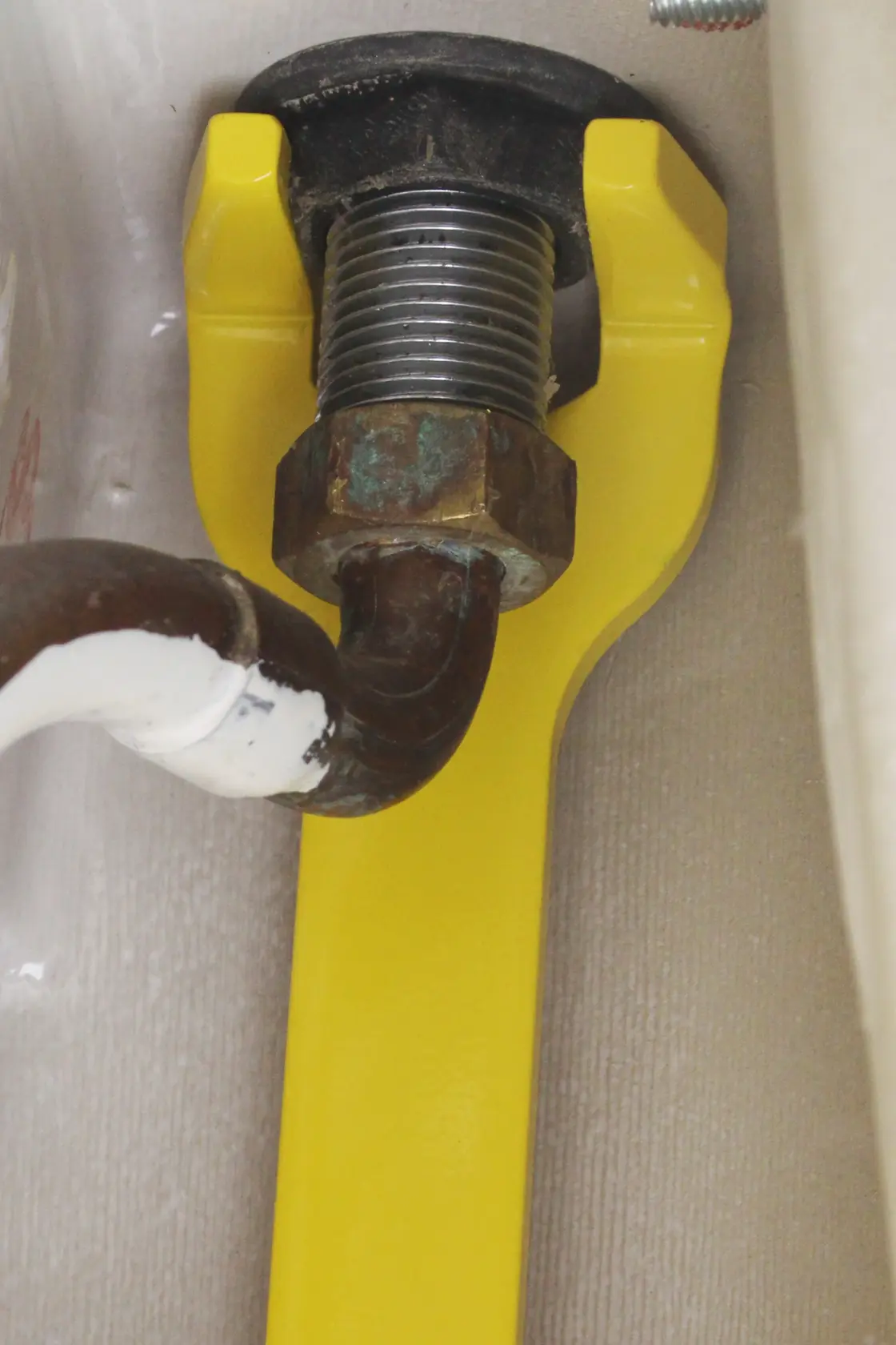 STANLEY 0-70-454 yellow pipe wrench in use on a metal plumbing fitting, close-up photo.