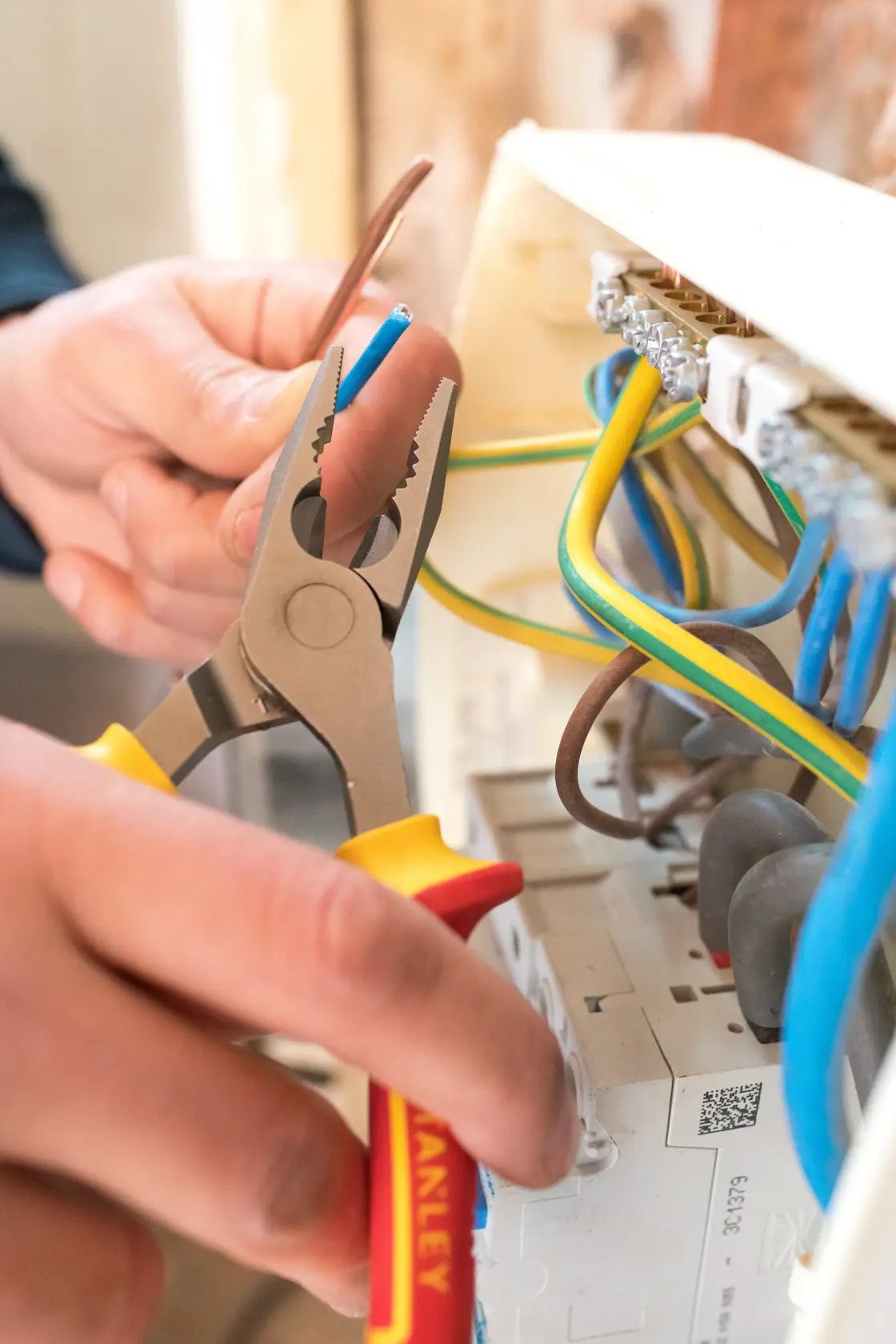 STANLEY 0-84-000 pliers being used to grip electrical wire inside a junction box.