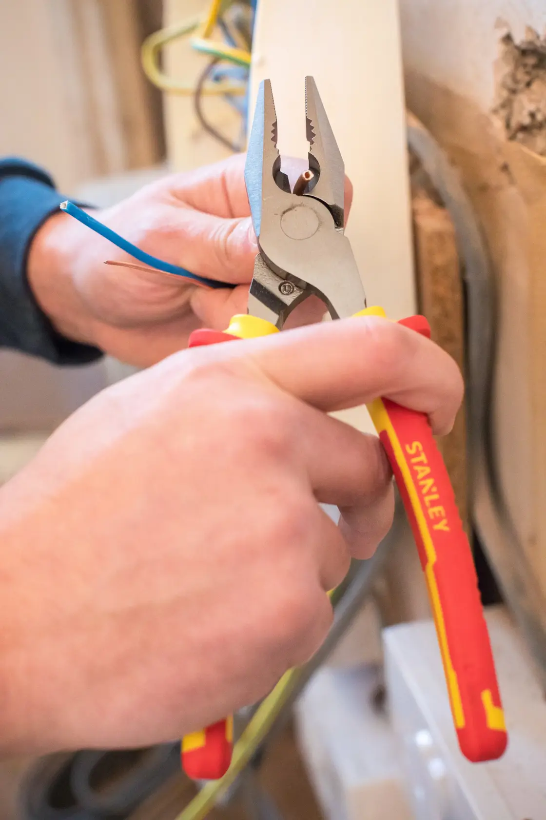 STANLEY 0-84-002 insulated pliers cutting electrical wire, close-up photography during installation.