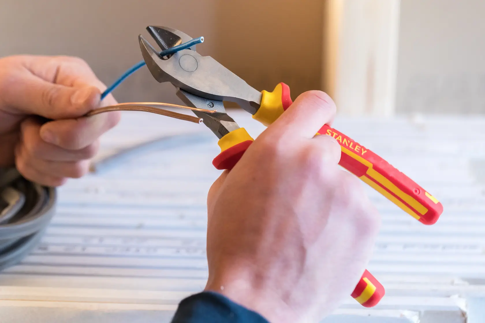 Stanley 0-84-004 insulated diagonal cutting pliers used to cut electrical wires, close-up in hand.