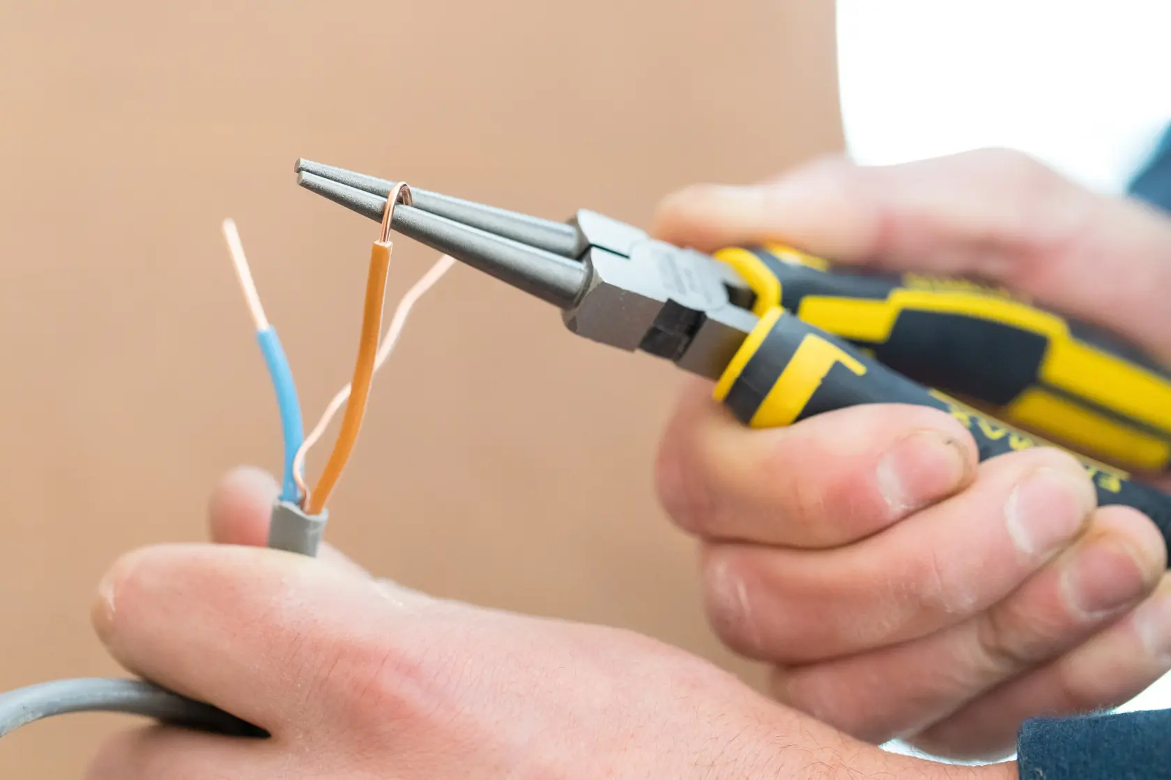 Photo of STANLEY 0-84-496 pliers in use, twisting copper wire, close-up with yellow and black handle.