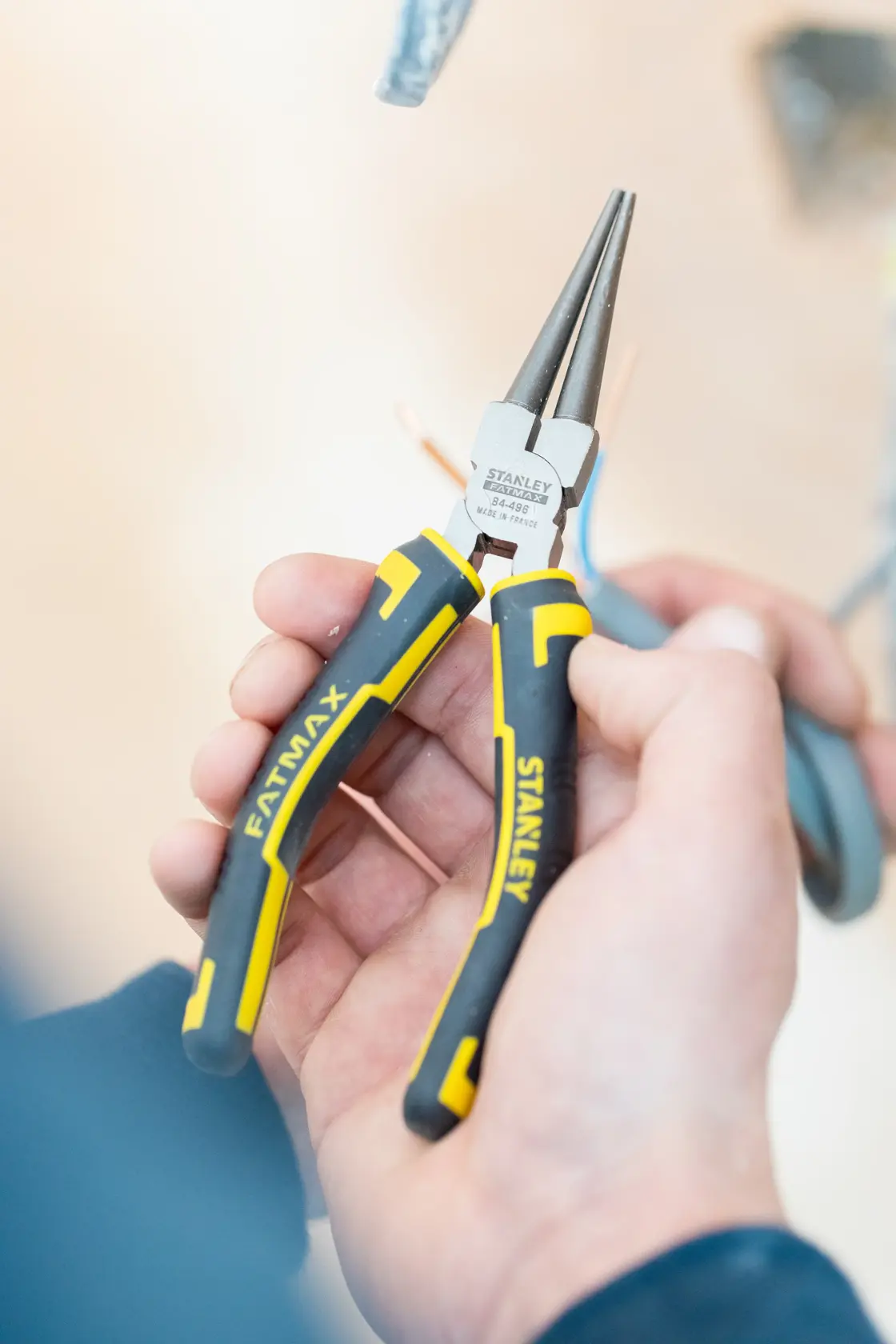 STANLEY 0-84-496 FATMAX long nose pliers with yellow and black handle, close-up in hand.