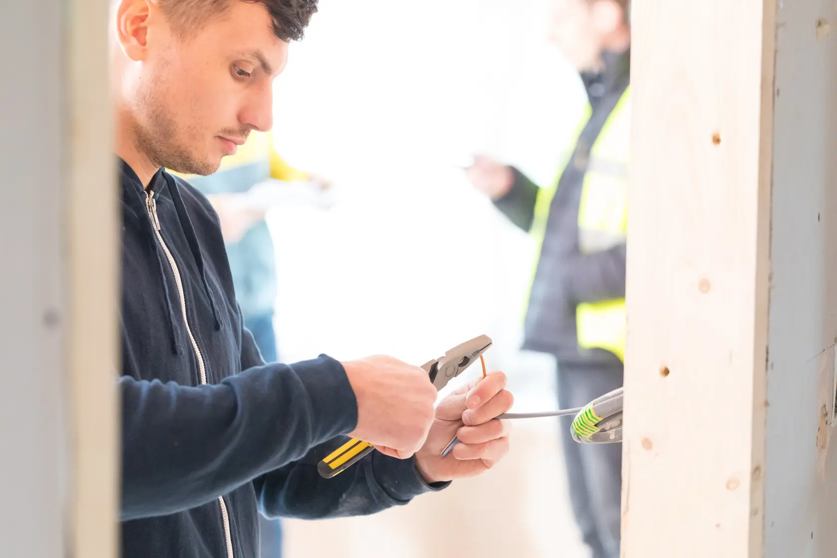 STANLEY 0-89-868 pliers in use by worker stripping wire in construction setting.