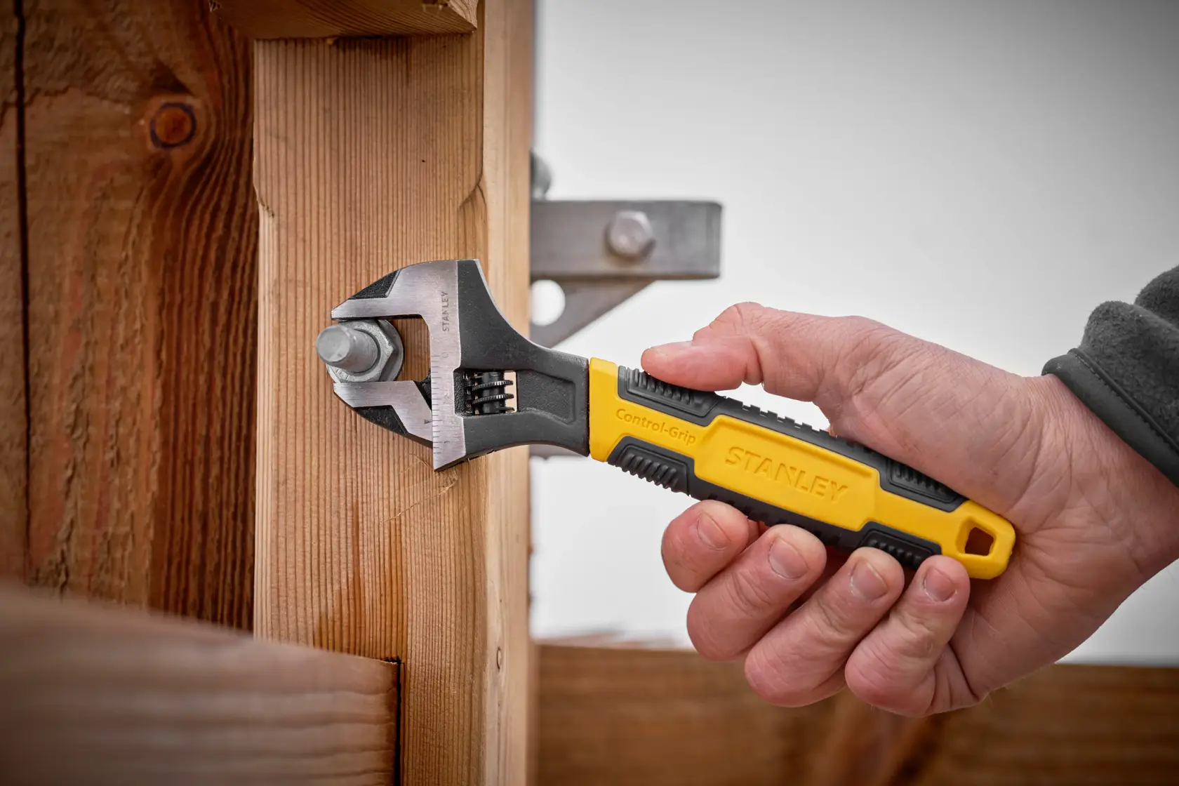 STANLEY 0-90-948 adjustable wrench with yellow and black handle used on bolt, photography.