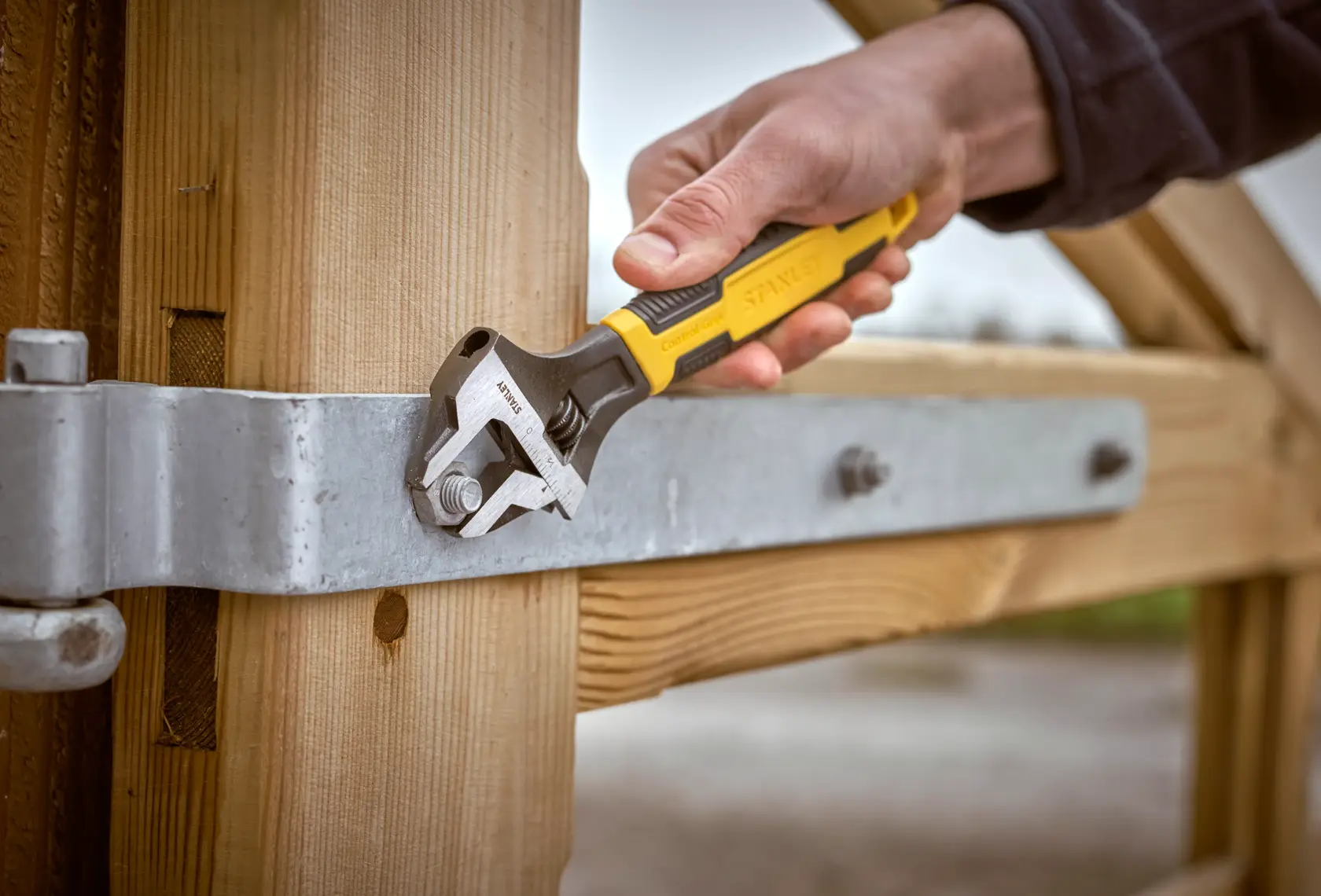 STANLEY 0-90-948 adjustable wrench used on a gate bolt, close-up outdoor photography.