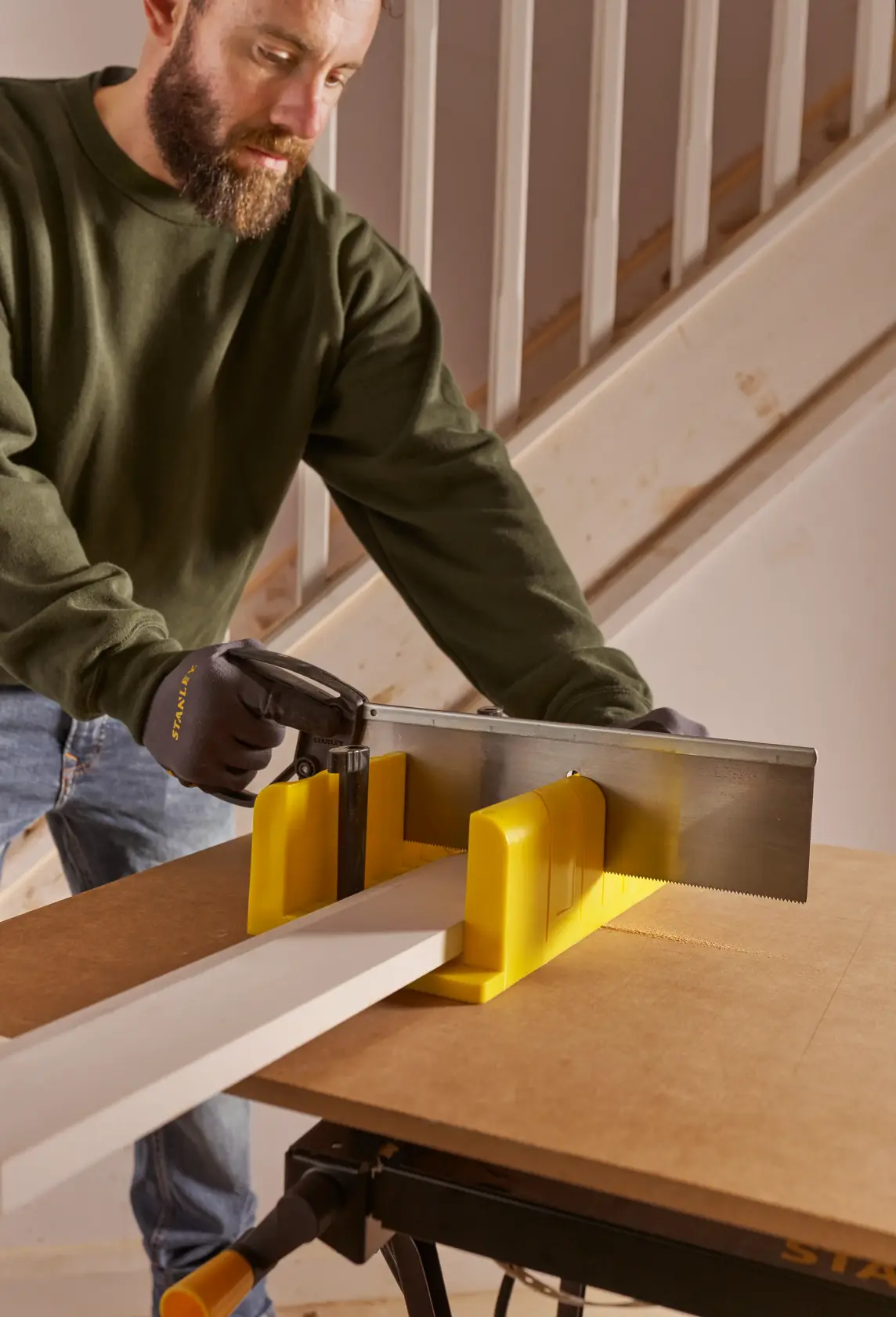 STANLEY 1-20-600 photography of yellow mitre box and saw in woodworking use, close side angle.