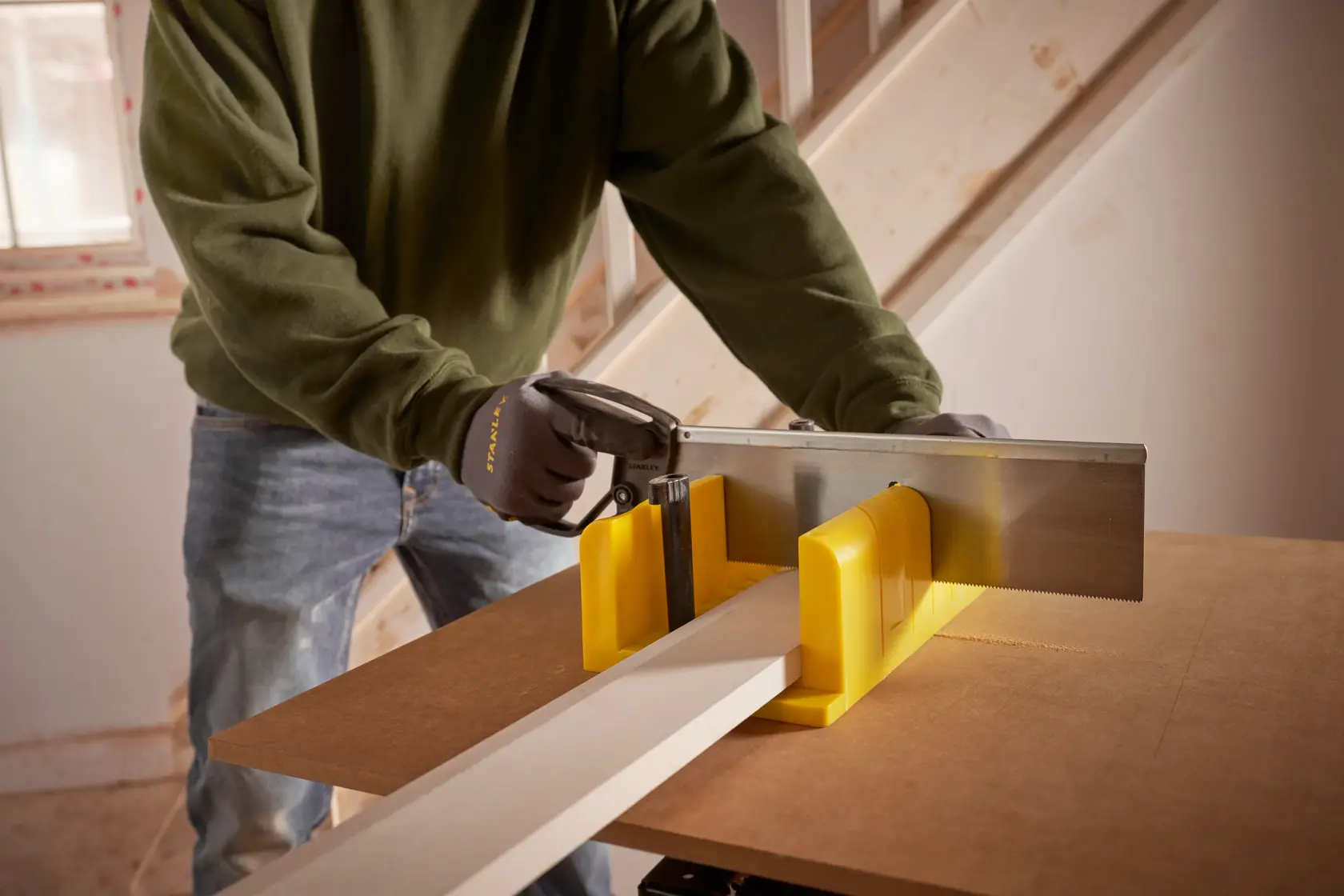 STANLEY 1-20-600 handsaw and yellow mitre box used to cut wood on a workbench, close-up angle.