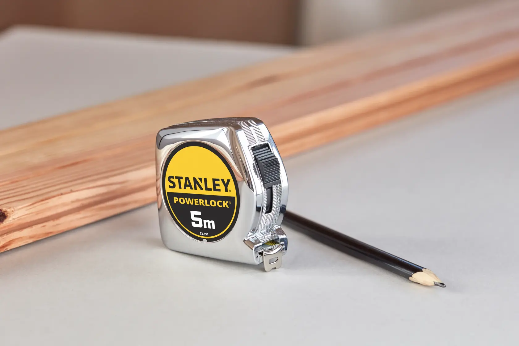 STANLEY 1-33-194 Maßband PowerLock 5m, Fotografie mit Bleistift und Holz im Hintergrund.