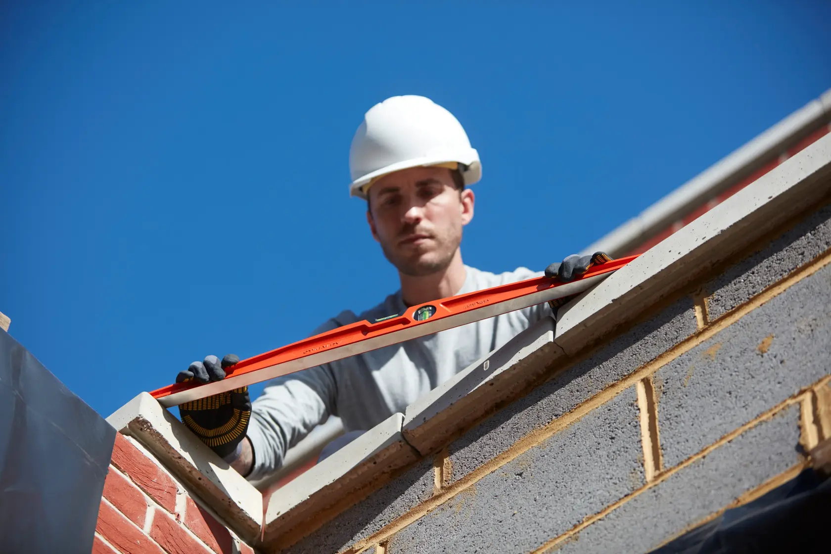 STANLEY 1-42-315 spirit level held by gloved worker on brick wall, outdoor construction scene.