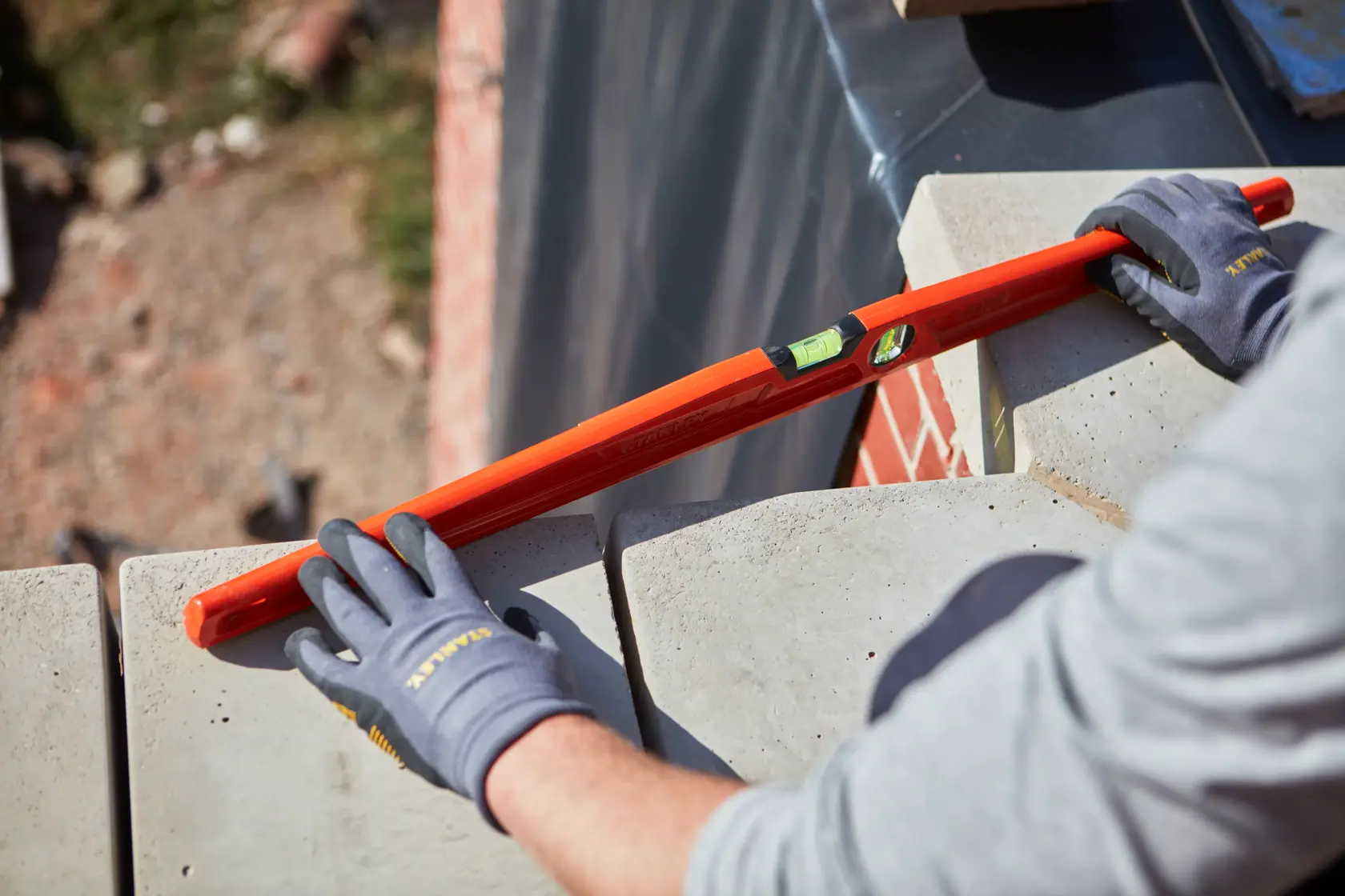 STANLEY 1-42-315 spirit level used on masonry by gloved hands, product photography, angled view.