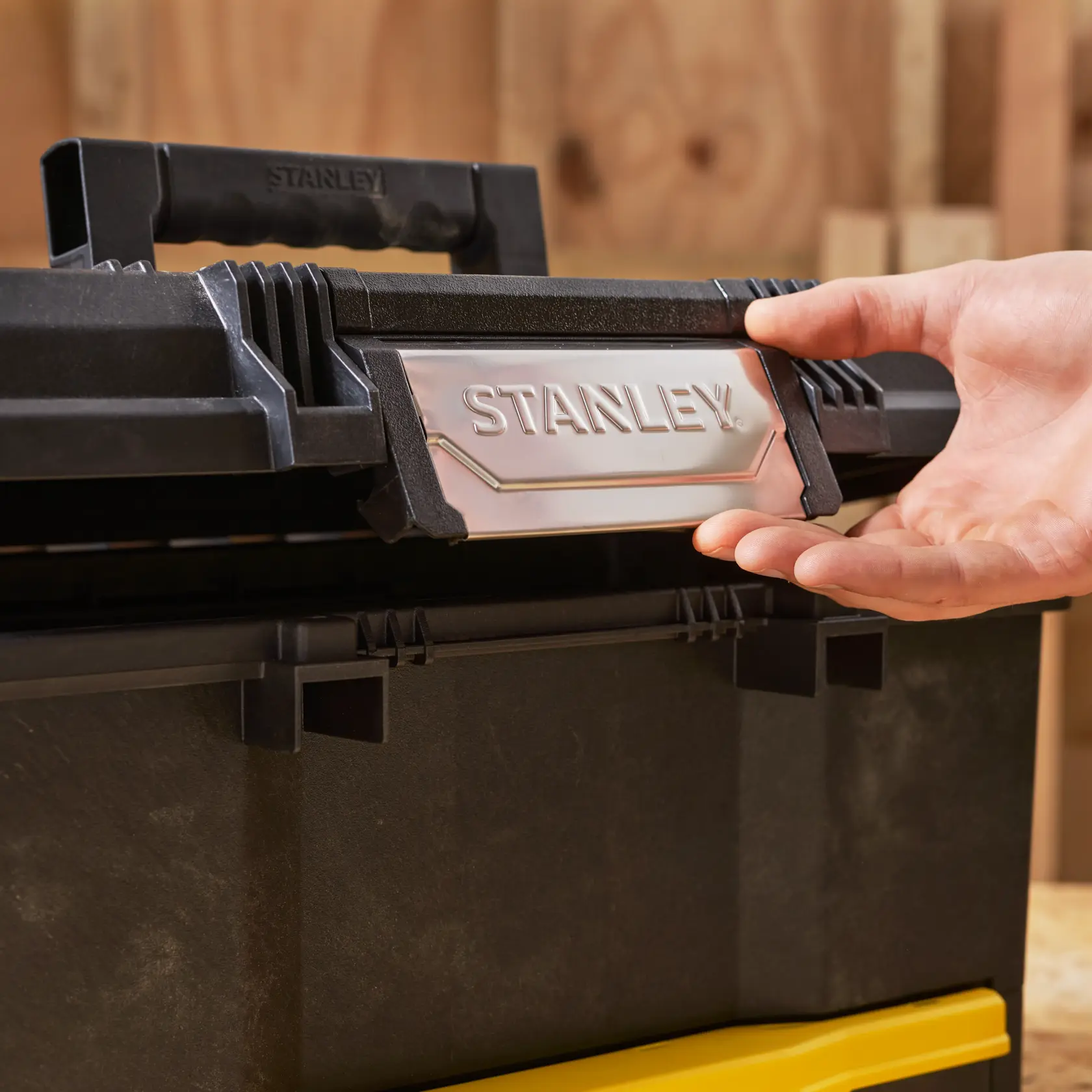 STANLEY 1-70-316 toolbox close-up with black and yellow plastic, hand opening latch.