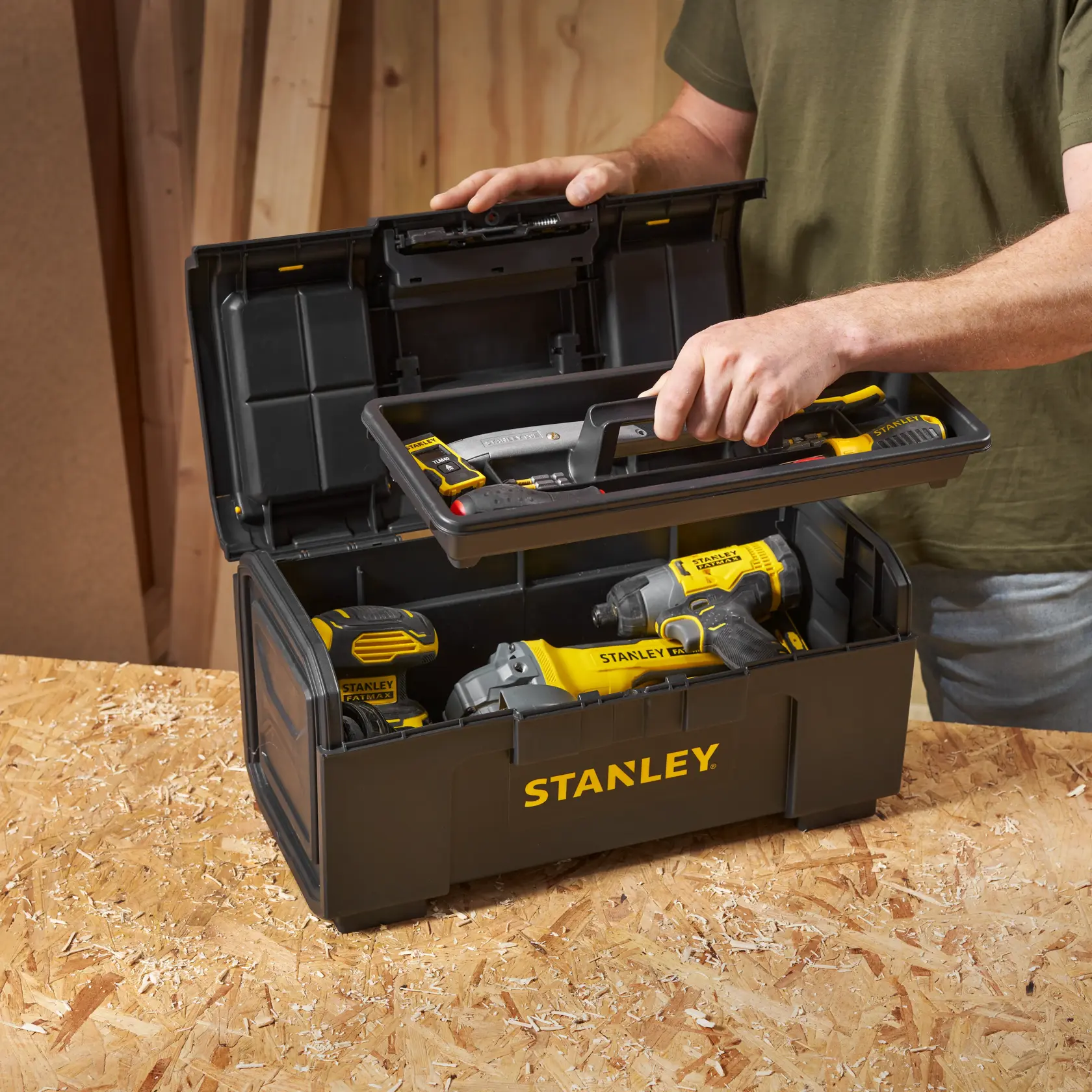 STANLEY 1-79-217 Werkzeugkasten mit gelb-schwarzen Elektrowerkzeugen, offen auf Werkbank, schräge Ansicht.