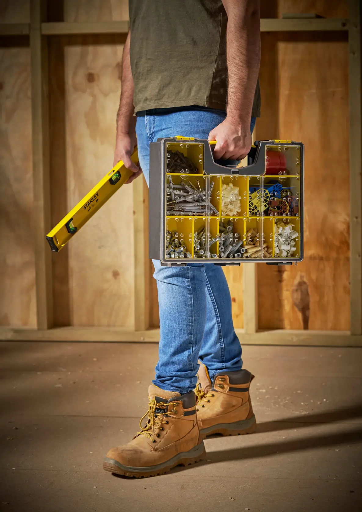 Photo of STANLEY 1-92-749 storage organizer with yellow compartments, carried by a person on a construction site.