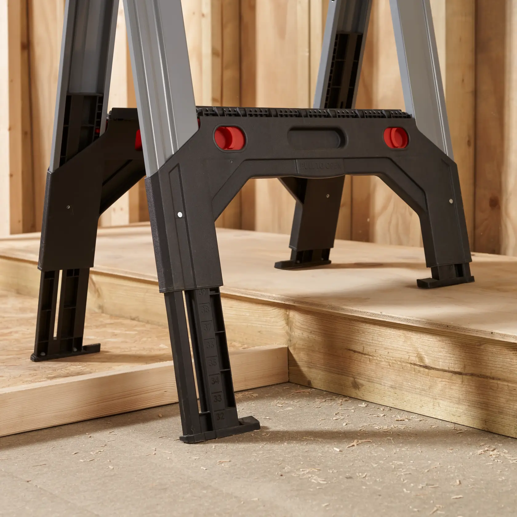 STANLEY 1-92-980 adjustable work platform legs with measurement markings, close-up side angle, on wooden floor.
