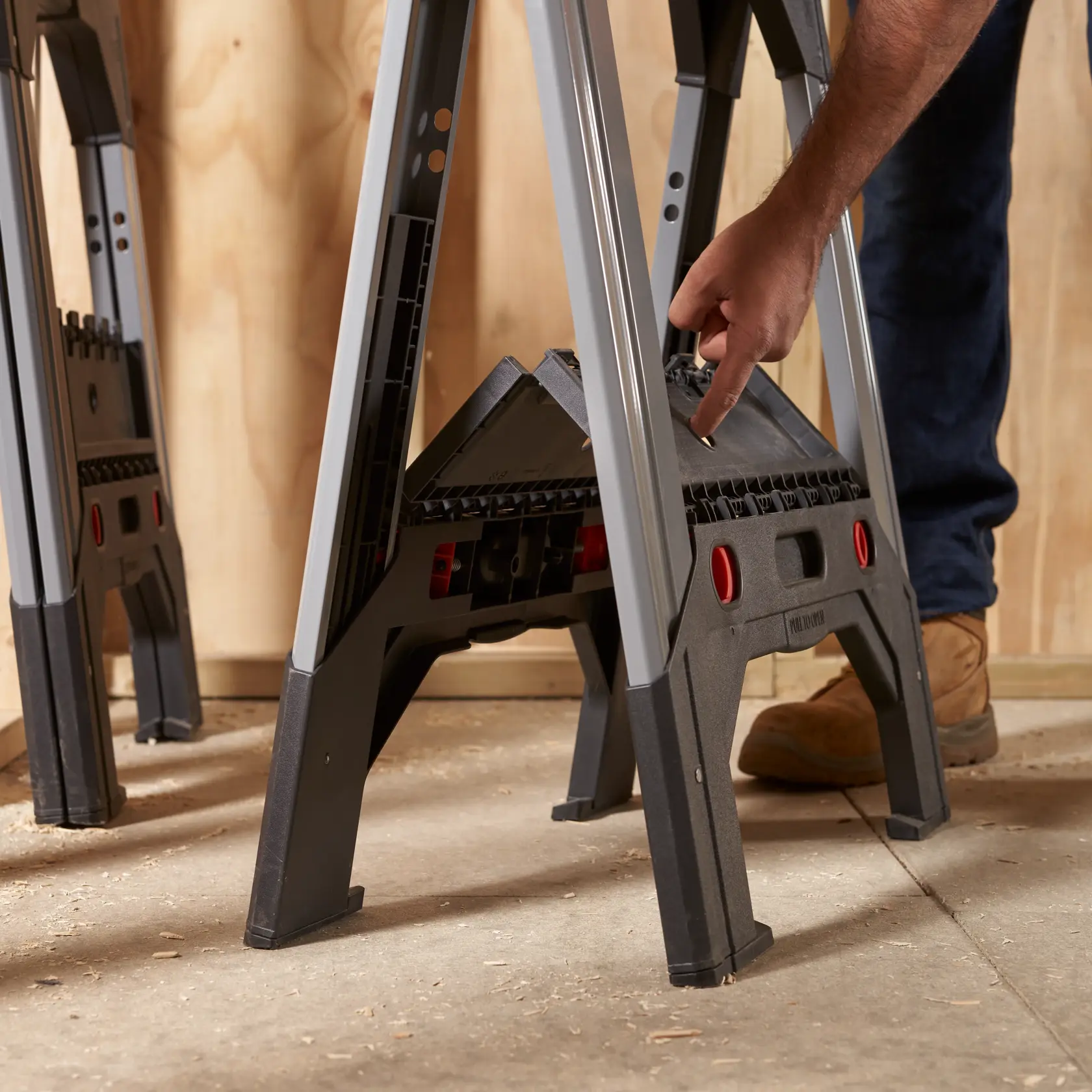STANLEY 1-92-980 sawhorse with black legs and red accents, shown in use on a workshop floor.