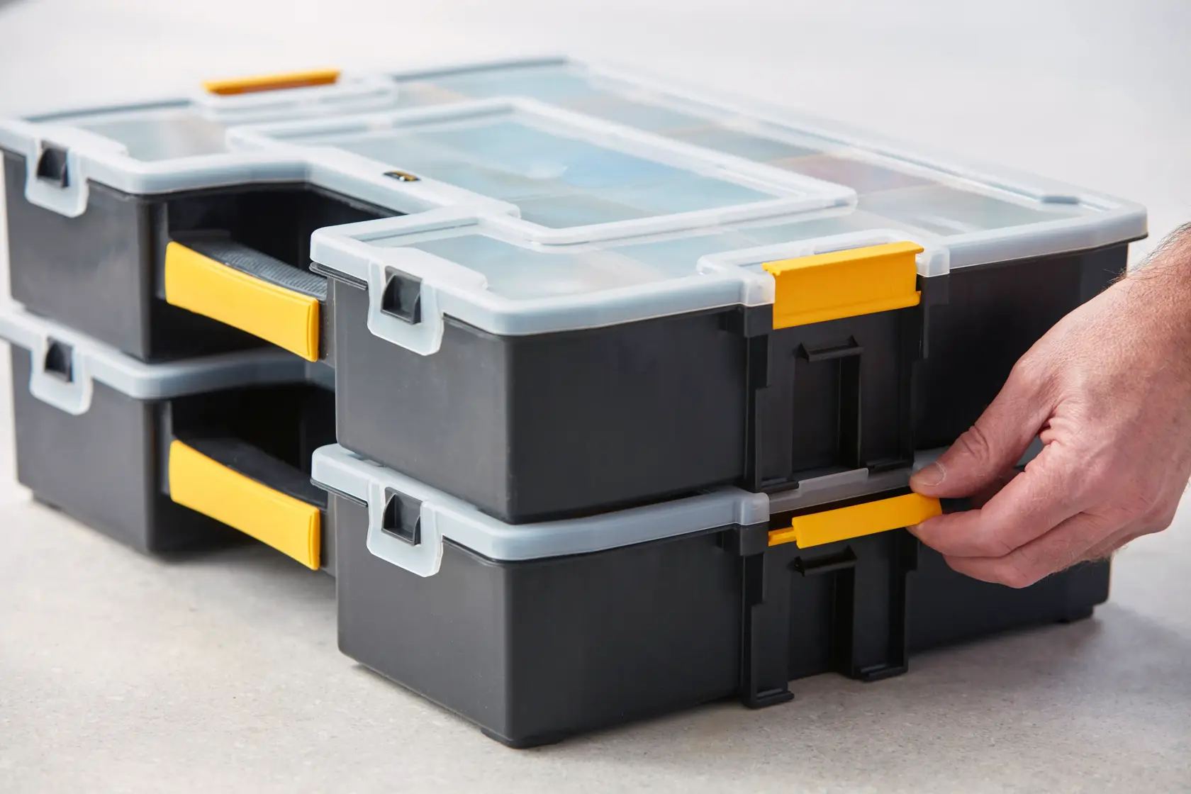 STANLEY 1-94-745 stapelbare schwarze und gelbe Organizer mit Klarsichtdeckeln, seitliche Nahaufnahme, Hand stellt Riegel ein.