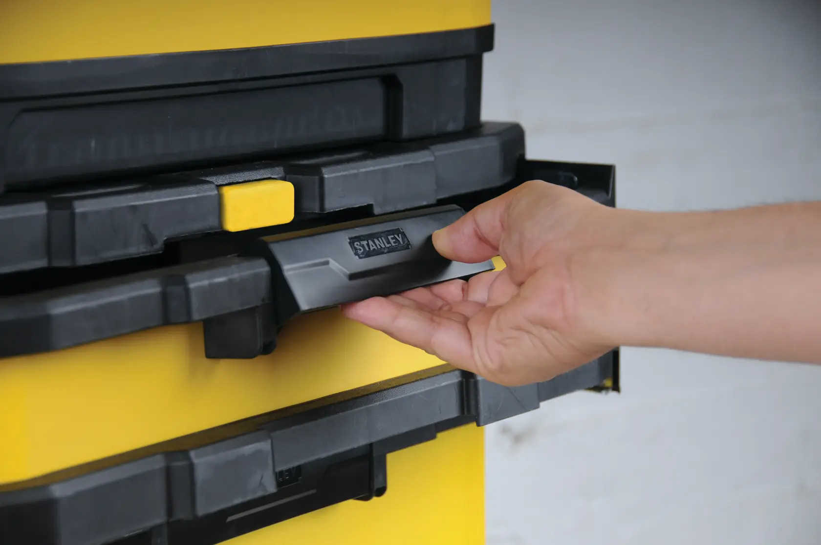 STANLEY 1-95-621 tool box stack with hand pulling front handle, close-up photography.