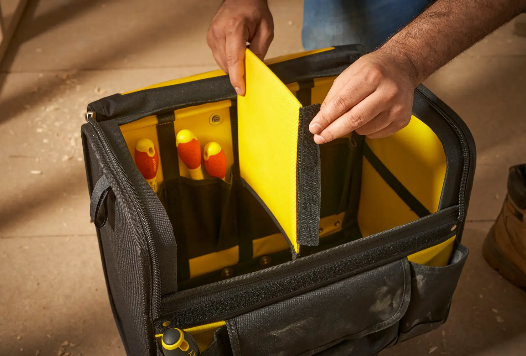 STANLEY 1-97-515 Werkzeugtasche mit gelber Inneneinteilung, Hand hält Einteiler, Vorderansicht.