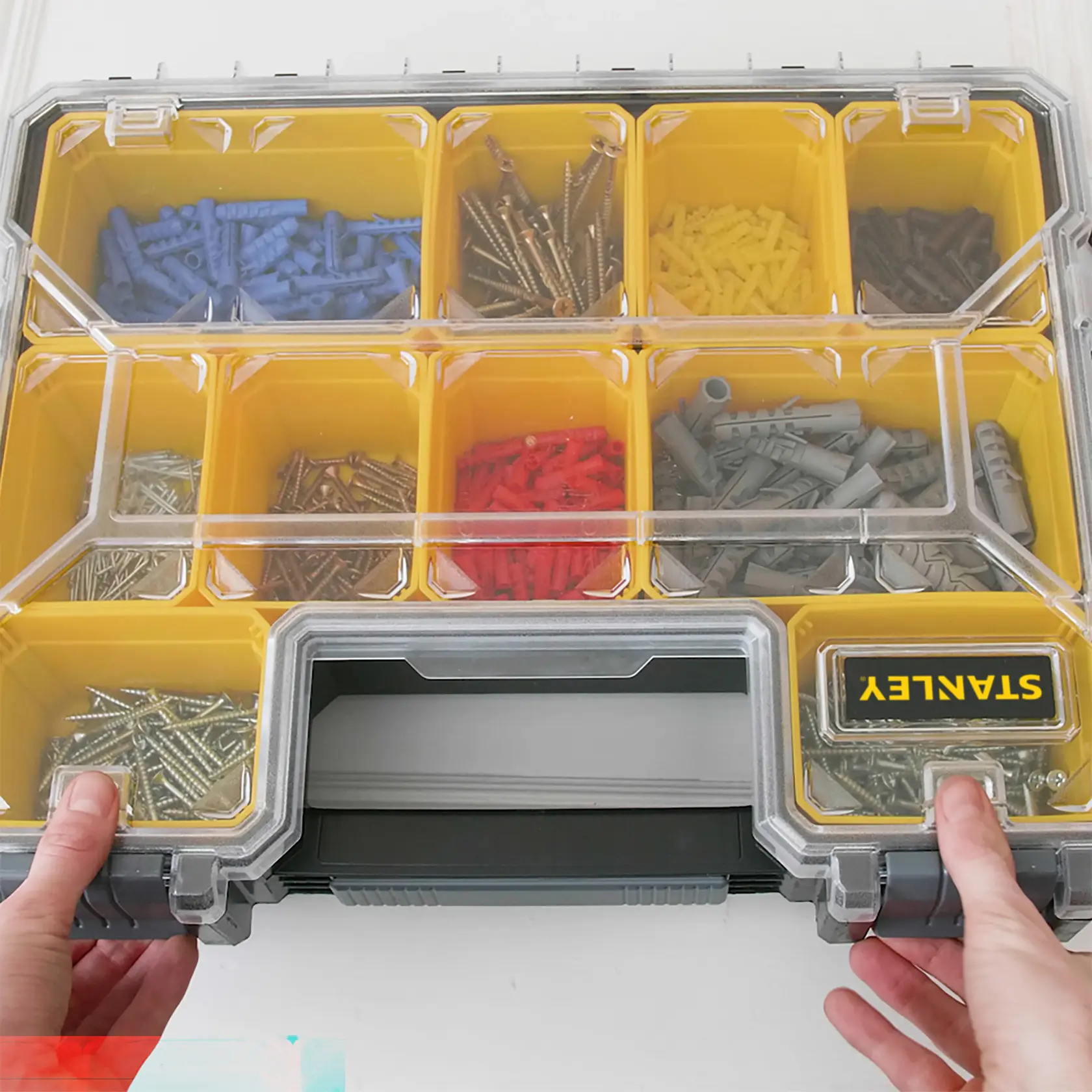 STANLEY 1-97-521 organizer box with yellow compartments, clear lid, assorted screws and wall plugs, top view.