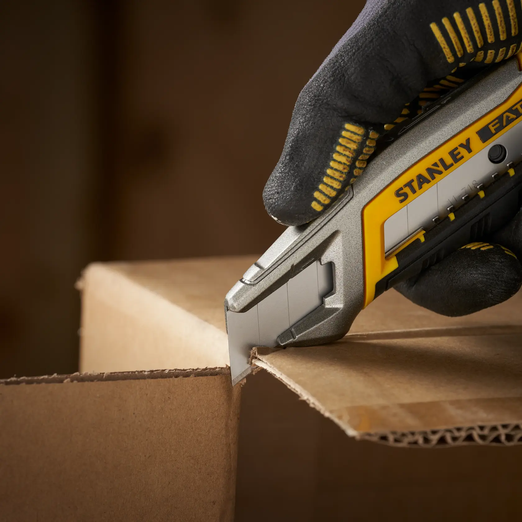 STANLEY 2-11-718 utility knife cutting cardboard, close-up photography, yellow and silver handle.