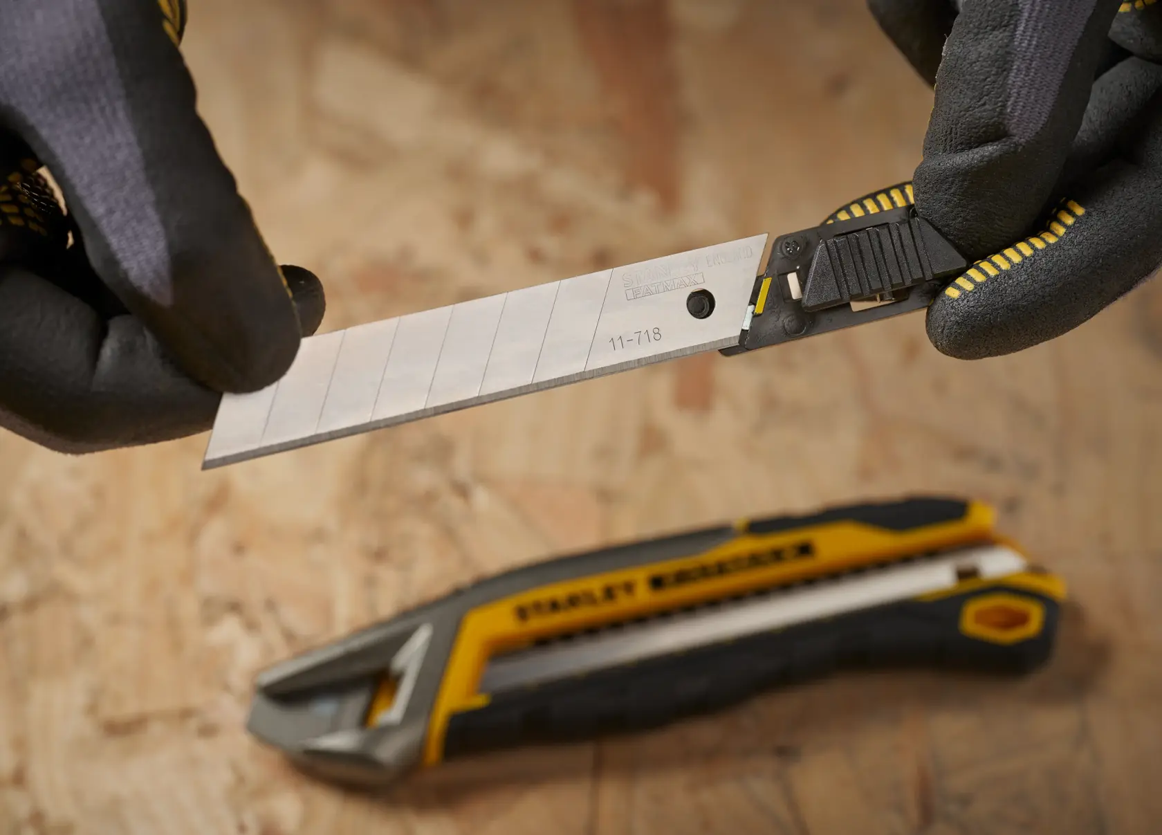 STANLEY 2-11-718 snap-off utility knife blade being installed into a yellow and black utility knife, close-up.