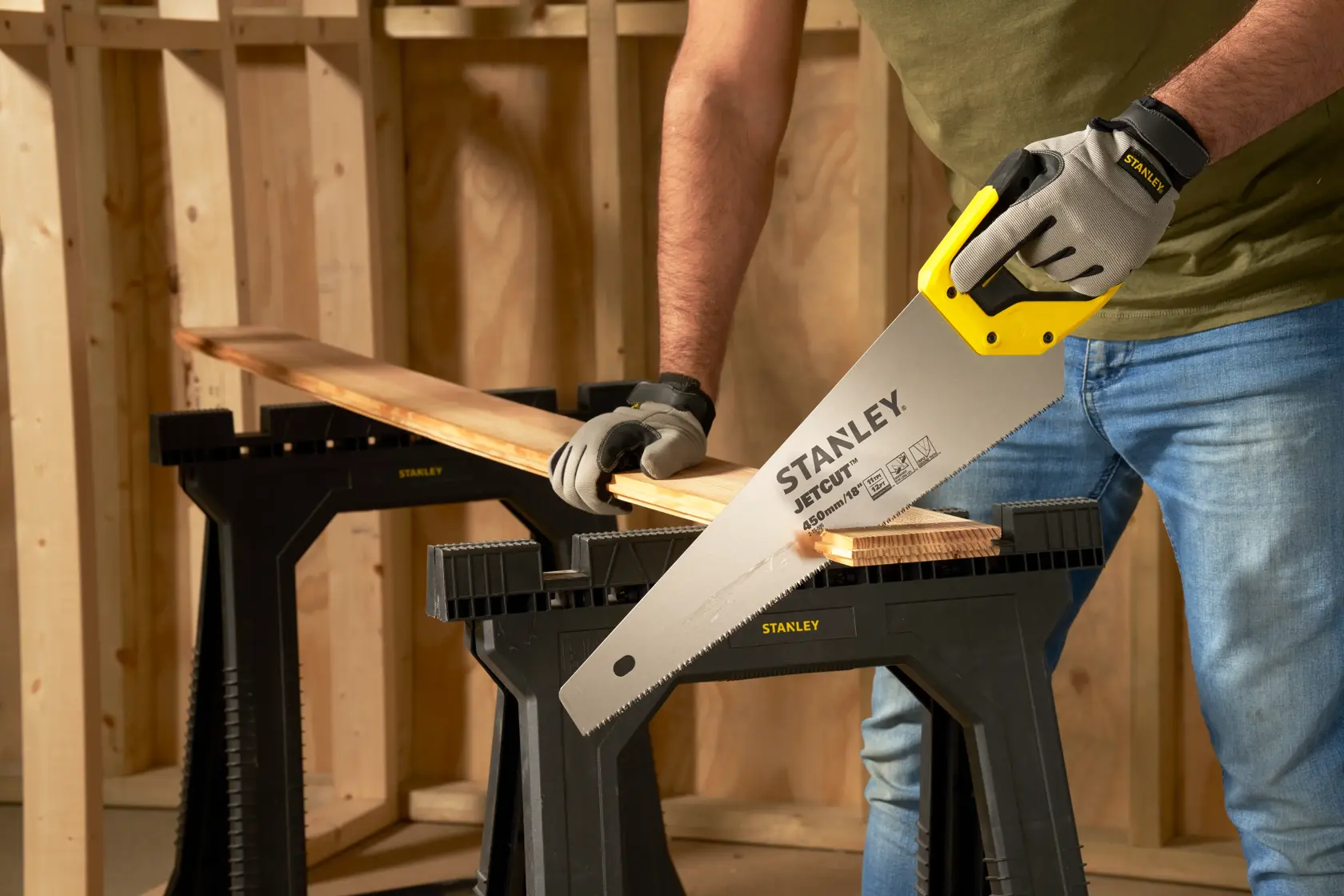 Foto der STANLEY 2-15-595 Handsäge beim Schneiden von Holz, Person mit Handschuhen in Werkstatt.