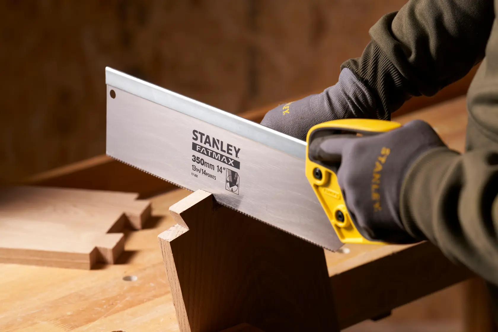 Photo of STANLEY 2-17-202 hand saw with yellow handle cutting wood, close-up in workshop setting.