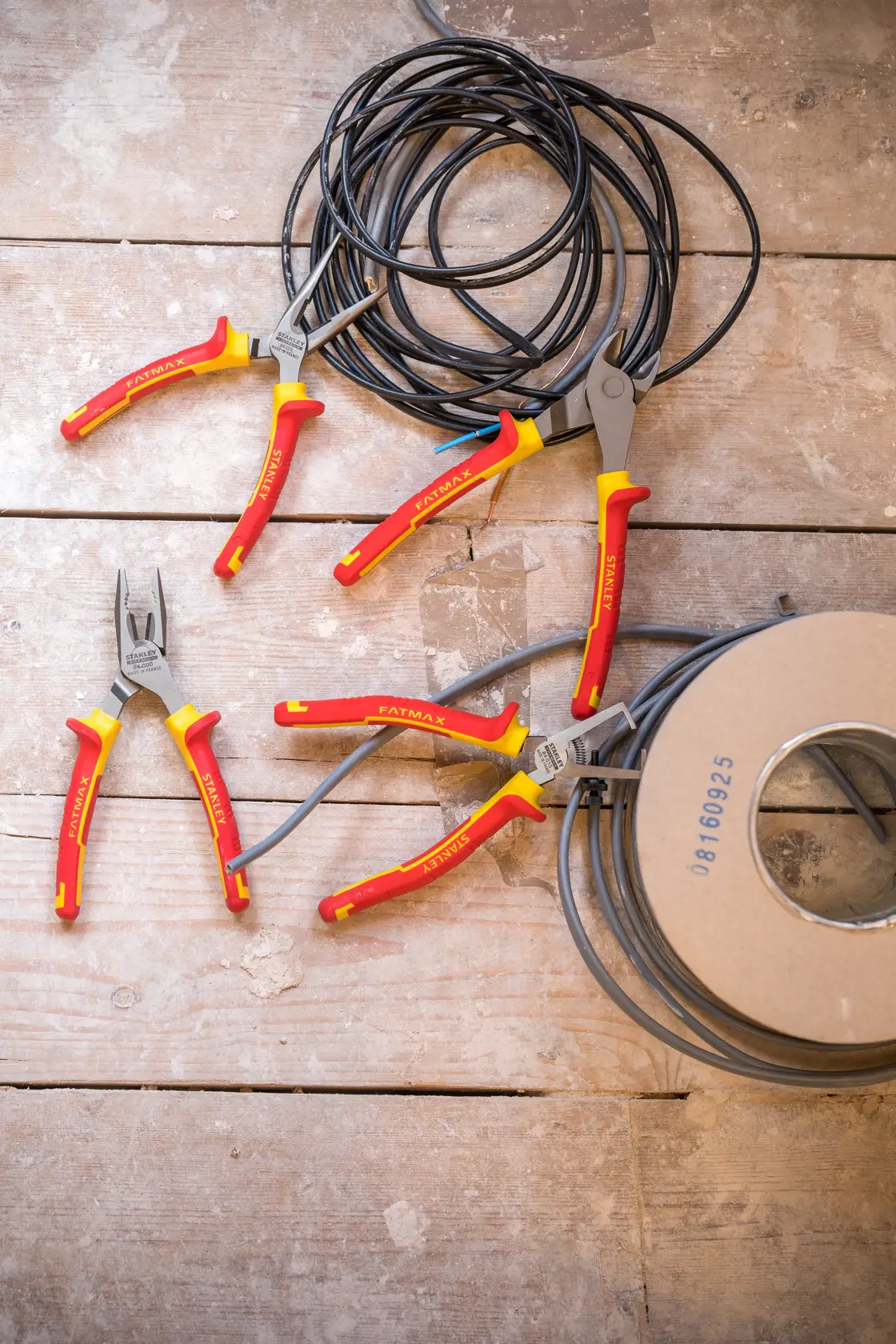 STANLEY 4-84-489 pliers set with red and yellow handles on wooden surface, shown with electrical wire, top view.