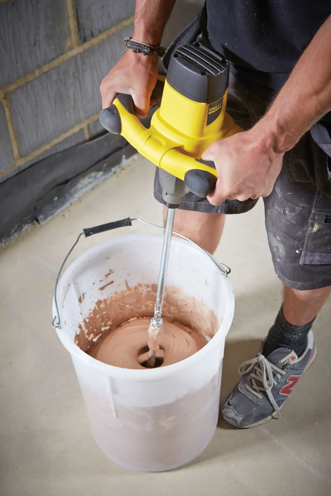 STANLEY FME190-QS mixer being used to blend material in a large white bucket on a construction site.