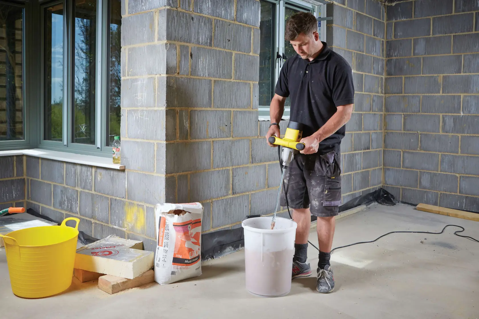 STANLEY FME190-QS paddle mixer used to mix material in a white bucket at a construction site.