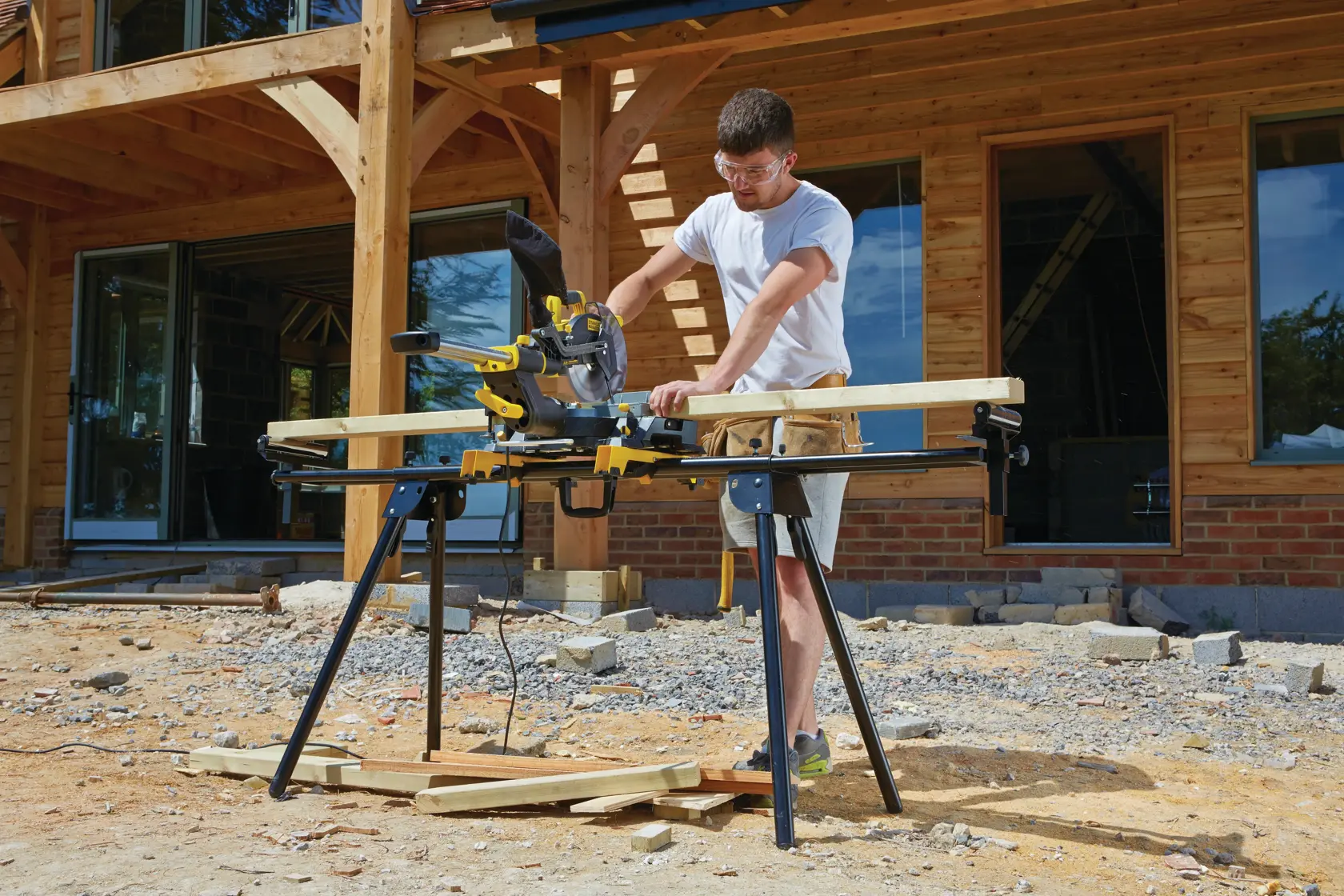 STANLEY FME721-QS miter saw in use outdoors on a building site, positioned on stand, cutting wood.