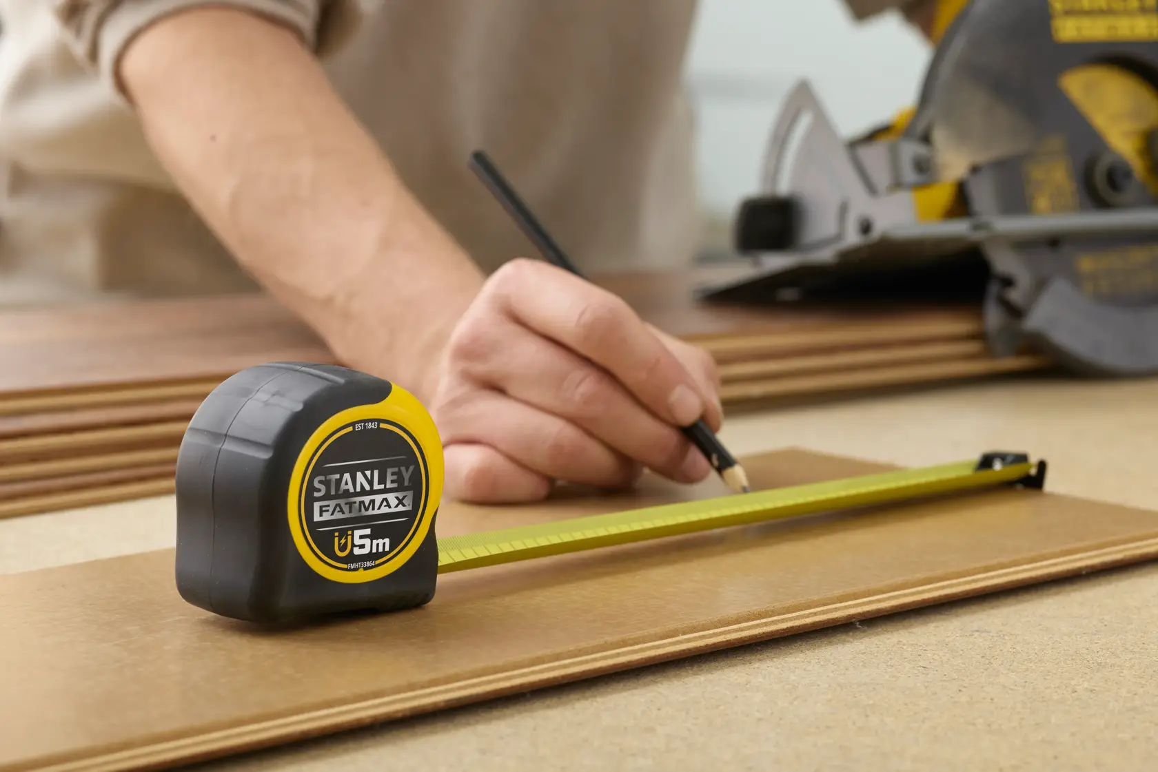 STANLEY FMHT0-33864 tape measure used for marking wood, yellow and black casing, close-up photography.