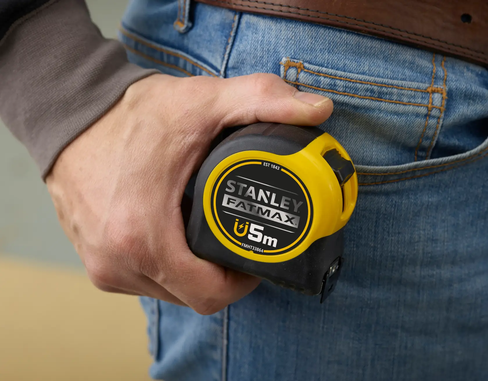 Stanley FMHT0-33864 tape measure held in hand, yellow and black, close-up photo.