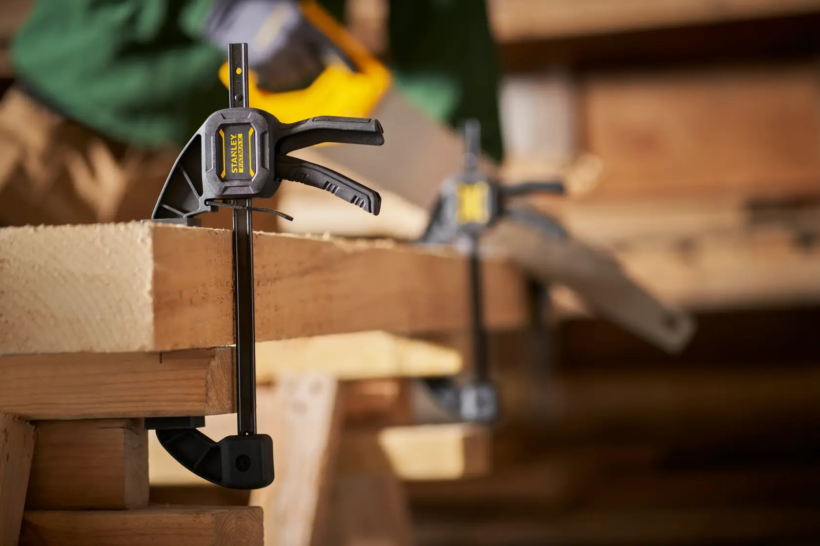 STANLEY FMHT0-83232 photography of quick grip clamp securing a wooden plank in workshop setting.