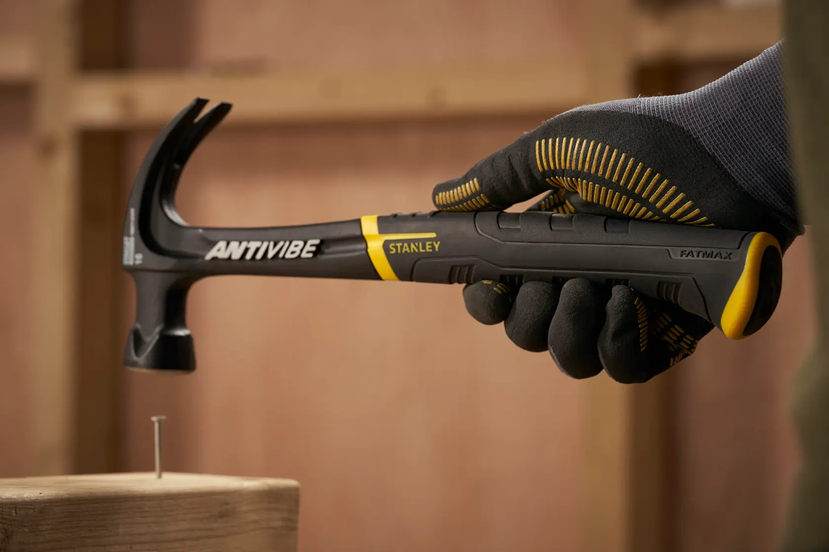 STANLEY FMHT1-51275 claw hammer with black and yellow handle held by gloved hand, FATMAX ANTIVIBE series.
