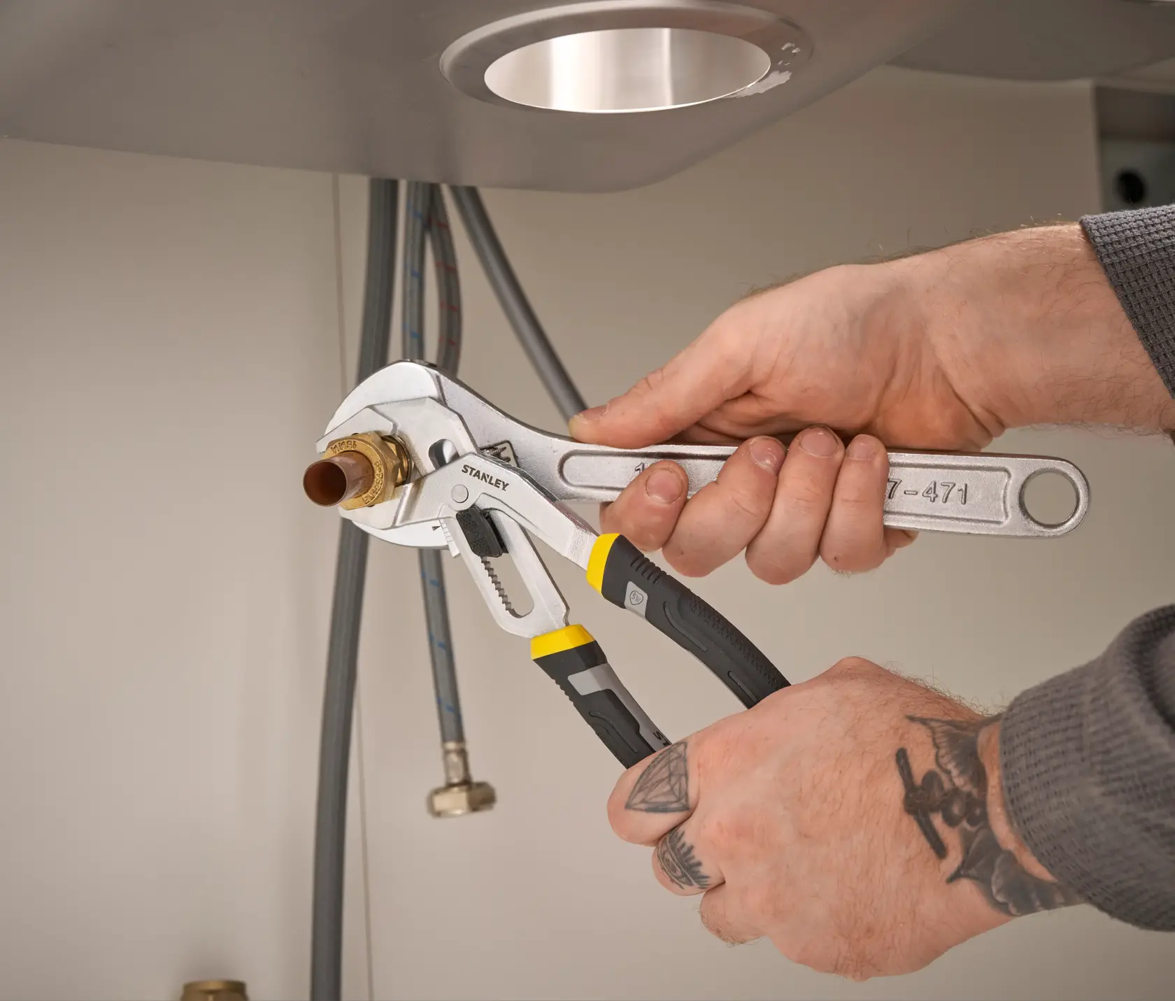 Photo of STANLEY FMHT75508-0 adjustable pliers gripping a pipe under a sink during plumbing work.