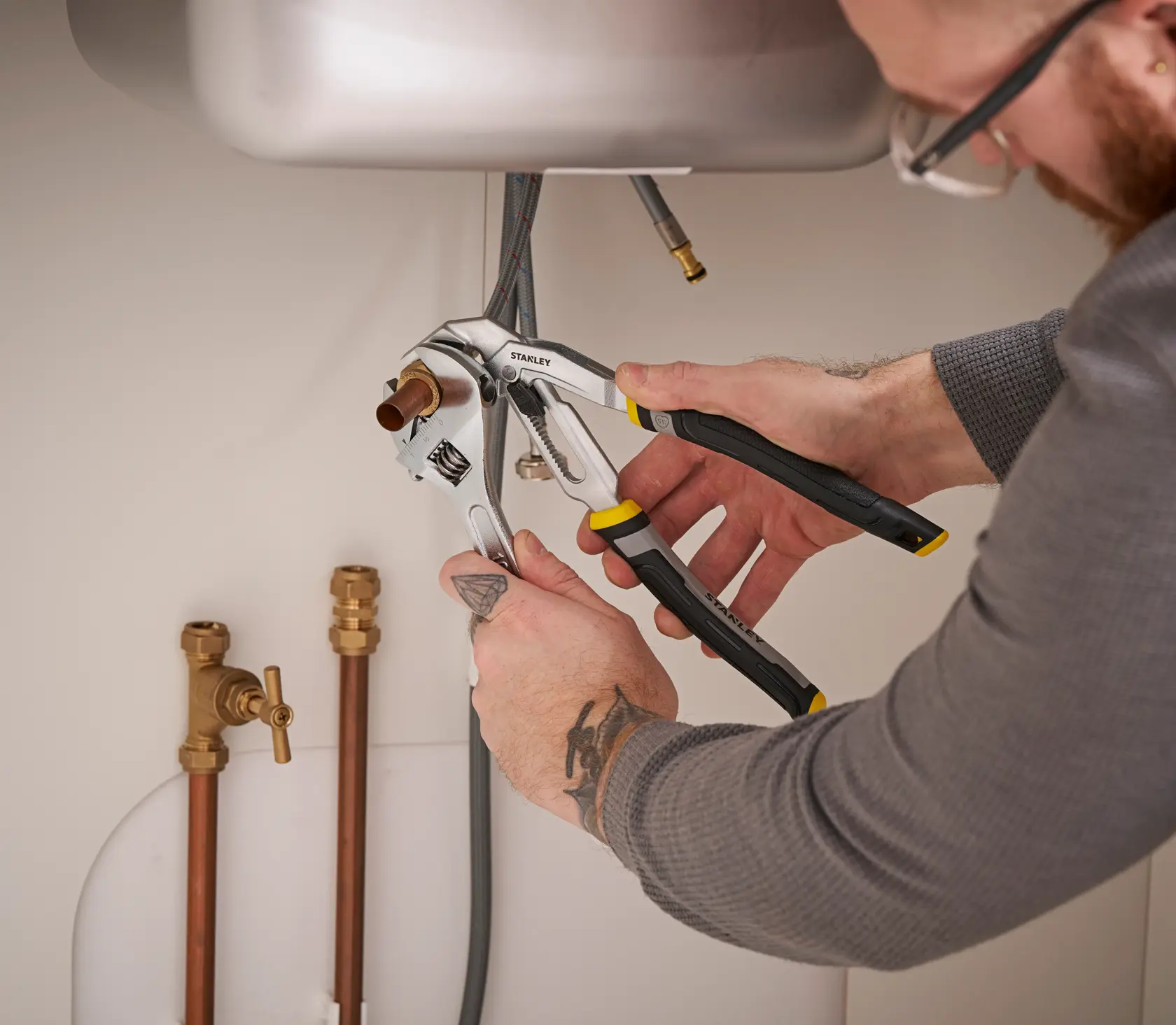 Photo of STANLEY FMHT75510-0 adjustable pliers in use by a person fixing plumbing under a sink.